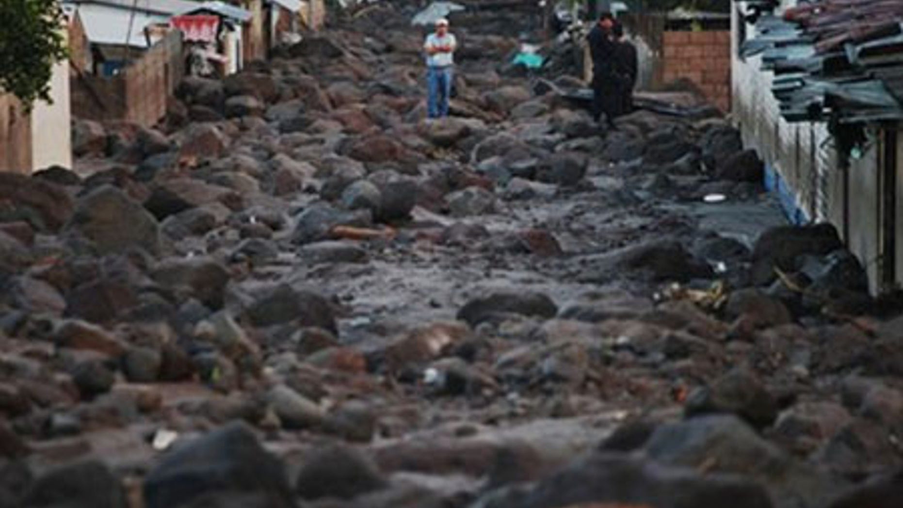 A man stands in a street covered with rocks from a landslide in Verapaz, some 125 km east from San Salvador, Monday, Nov. 9, 2009.