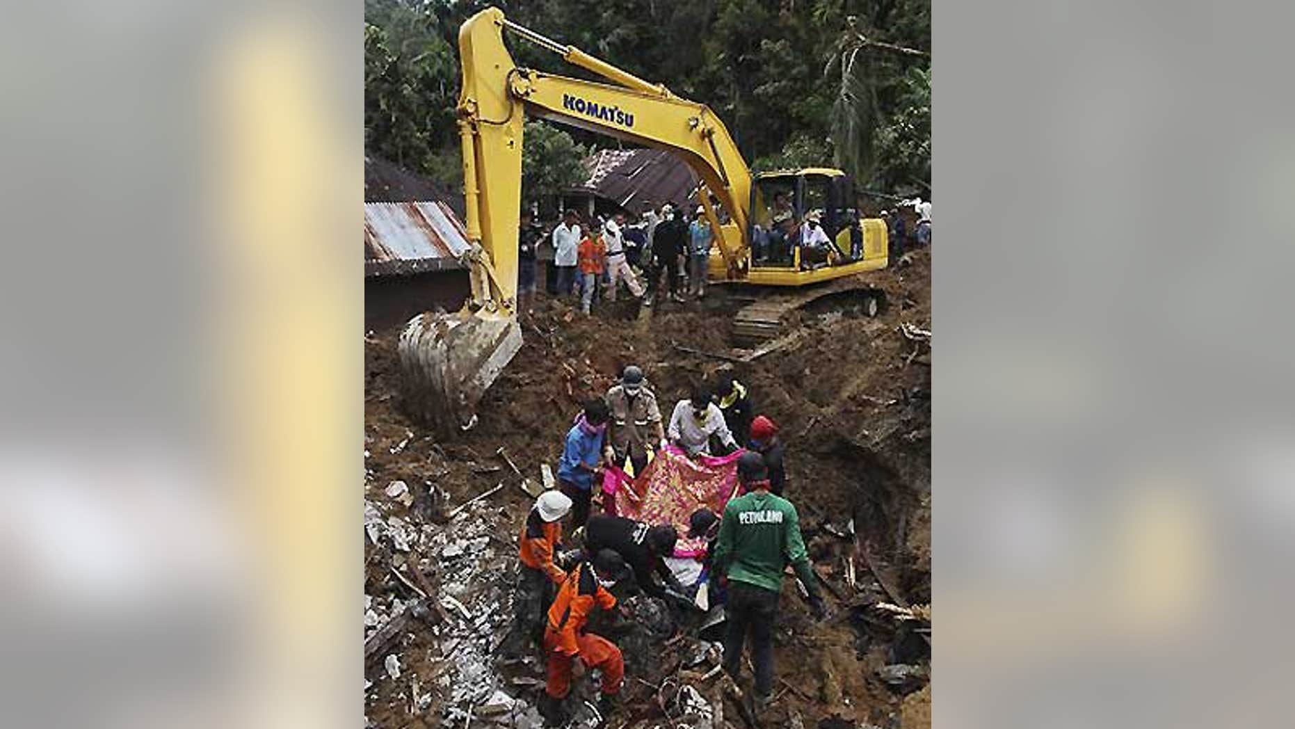 Oct. 4: Indonesian rescue volunteers cover a body before removing it from an area hit by landslides in the Sumatran Island village of Jumanak.