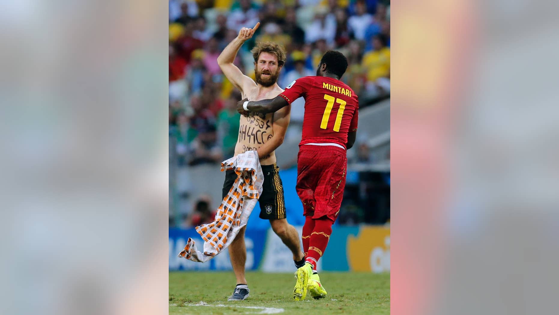 Ghana's Sulley Muntari assists a man off the pitch after he ran on during the group G World Cup soccer match between Germany and Ghana at the Arena Castelao in Fortaleza, Brazil, Saturday, June 21, 2014. (AP Photo/Frank Augstein)