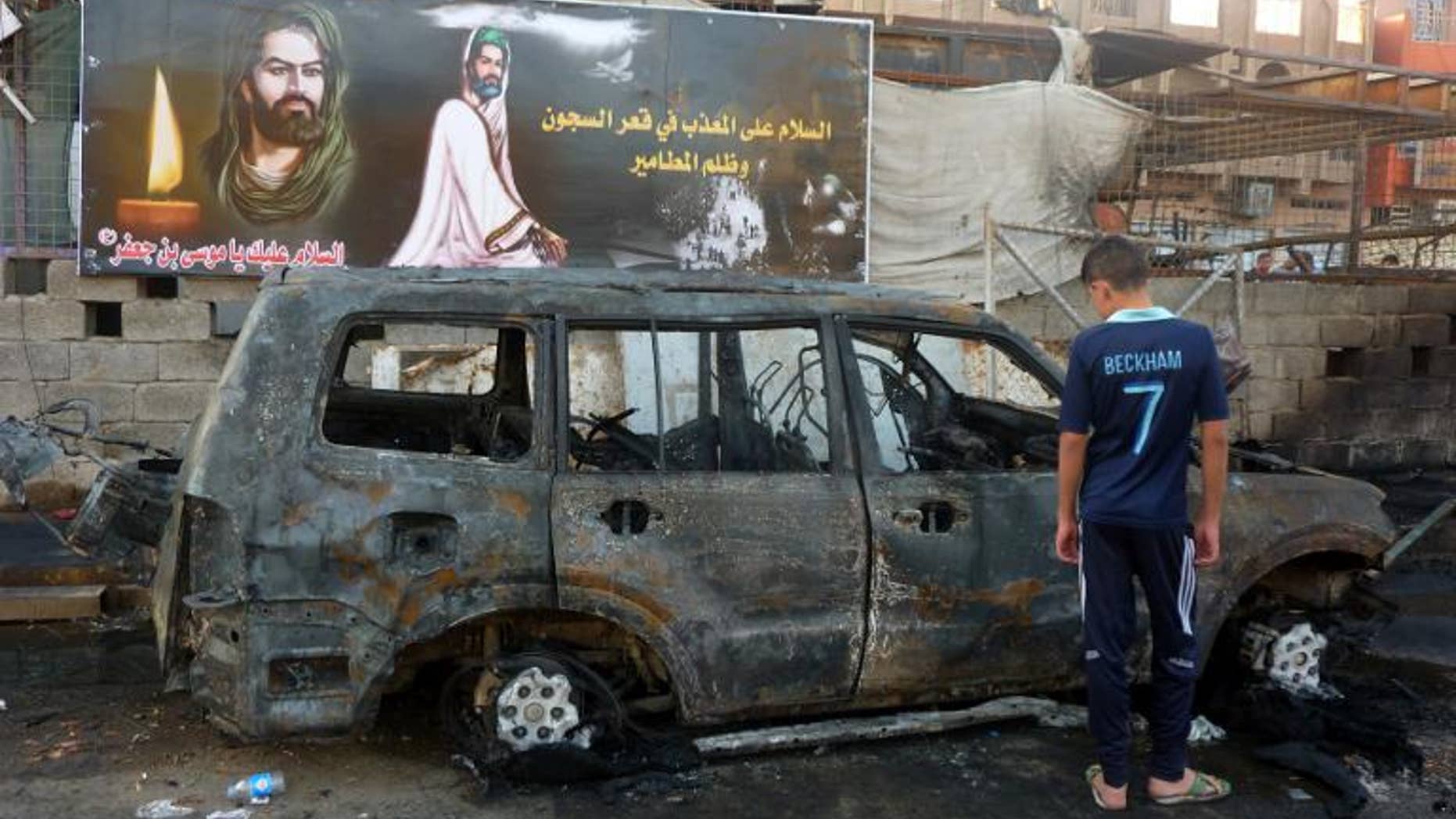 An Iraqi boy inspects a burnt out vehicle the day after a bombing in the Sadr City district of Baghdad, on September 22, 2103