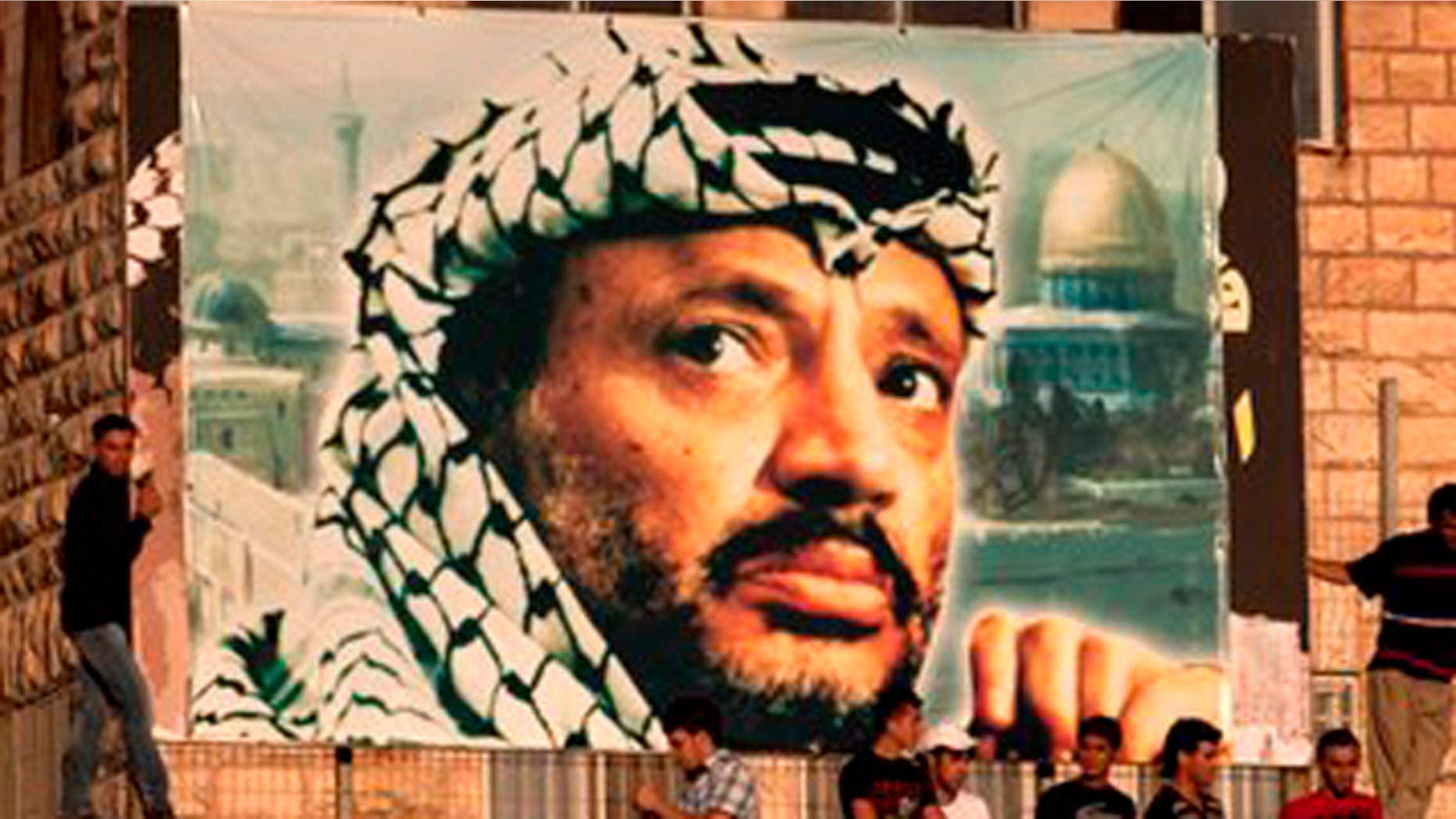 In this July 28, 2011 file photo, Palestinian soccer fans sit under a large banner showing late Palestinian leader Yasser Arafat during a World Cup qualifier game against Thailand in the West Bank city of Ramallah.