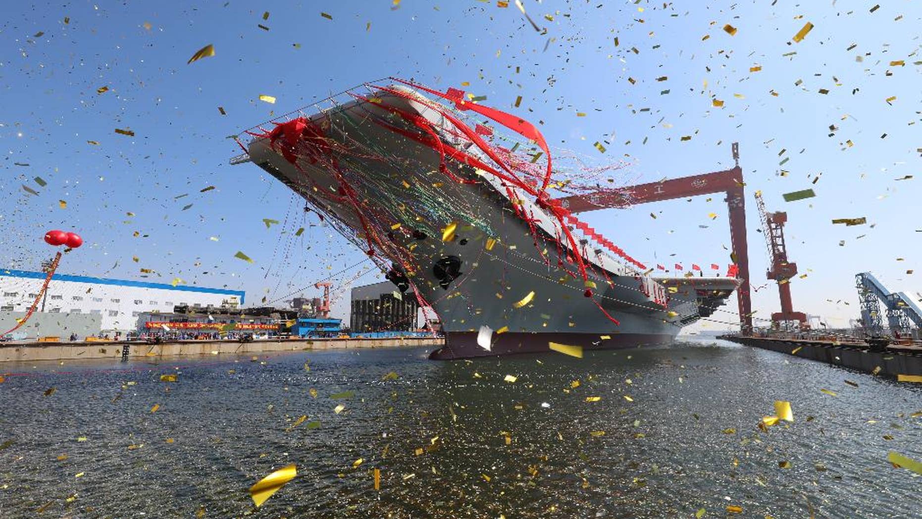 In this photo released by China's Xinhua News Agency, a newly-built aircraft carrier is transferred from dry dock into the water at a launch ceremony at a shipyard in Dalian in northeastern China's Liaoning Province, Wednesday, April 26, 2017. China launched its first aircraft carrier built entirely on its own on Wednesday, in a demonstration of the growing technical sophistication of its defense industries and determination to safeguard its maritime territorial claims and crucial trade routes. (Li Gang/Xinhua via AP)