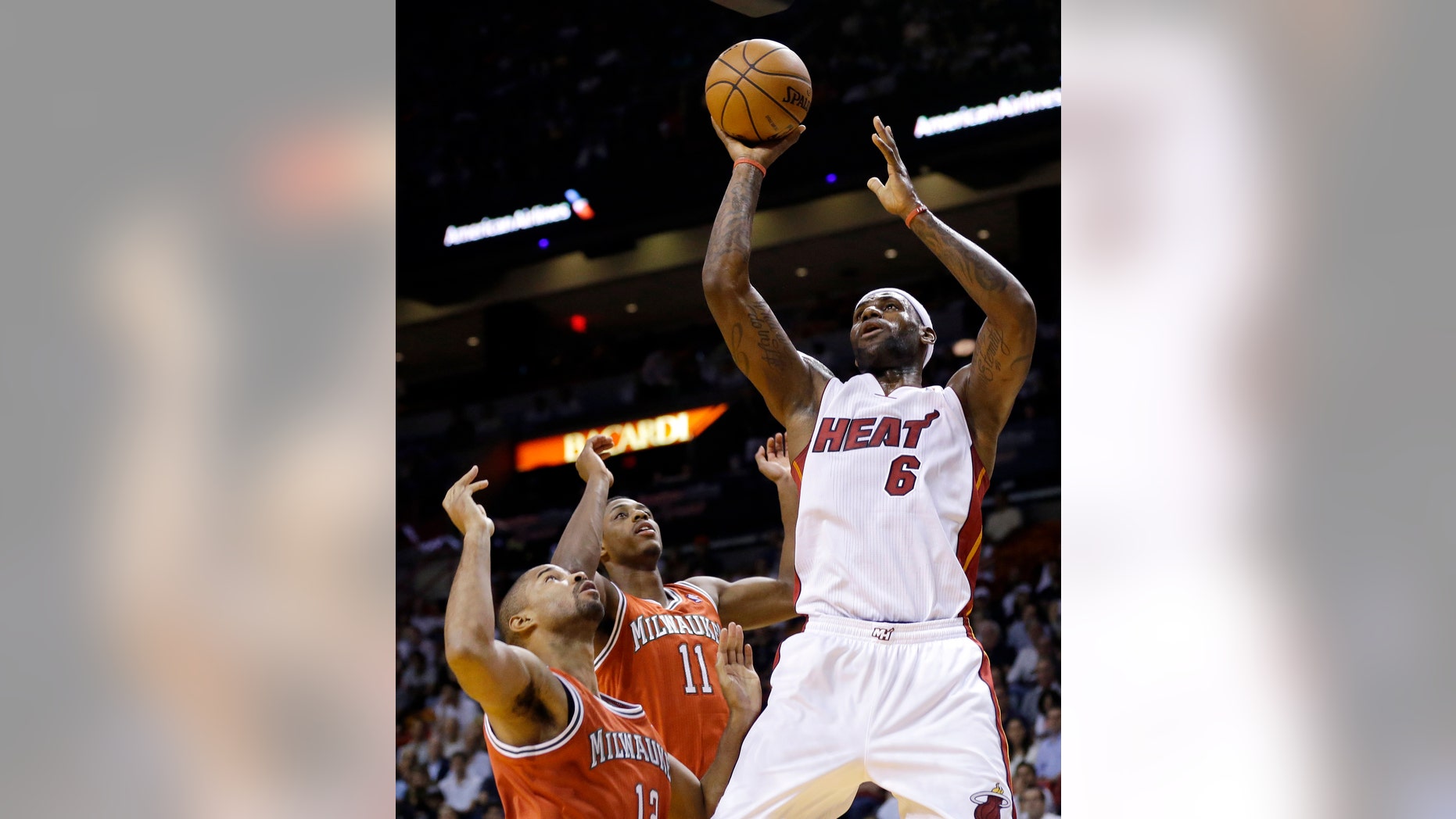 Miami Heat's LeBron James (6) shoots over Milwaukee Bucks' Gary Neal, left, and Brandon Knight (11) during the first half of an NBA basketball game Tuesday, Nov. 12, 2013, in Miami. (AP Photo/Lynne Sladky)
