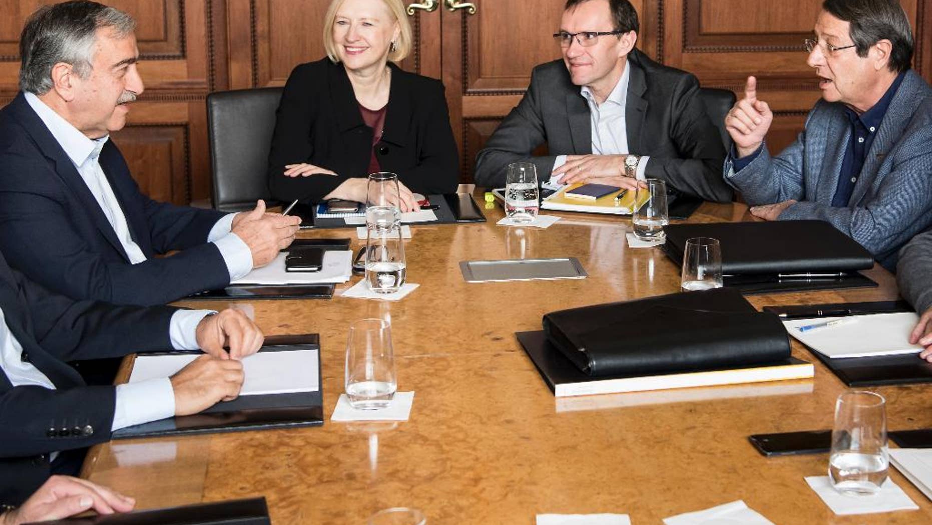 Turkish Cypriot leader Mustafa Akinci, left, speaks with Greek Cypriot President Nicos Anastasiades, right, next to Special Adviser to the United Nations Secretary-General on Cyprus Espen Barth Eide, 2nd right, and Elizabeth Spehar, Deputy to the Secretary-General's Special Adviser on Cyprus, 2nd left, during the Cyprus Talks, in Mont Pelerin, Switzerland Sunday, Nov. 20, 2016. (Jean-Christophe Bott/Keystone via AP)