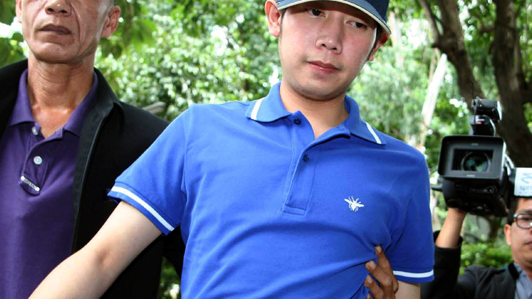 Sept. 3, 2012: Vorayuth Yoovidhya, a grandson of late Red Bull founder Chaleo Yoovidhaya, is taken by a plain-clothes police officer for investigation in Bangkok, Thailand.