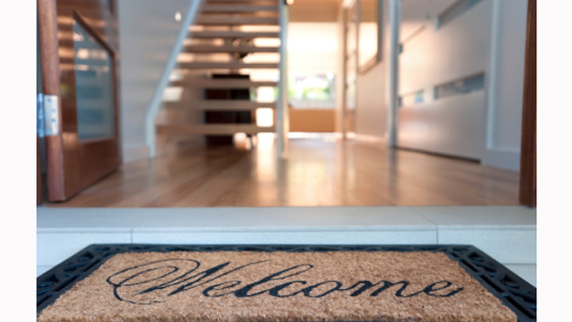 Close up of a welcome mat in front of an inviting house.