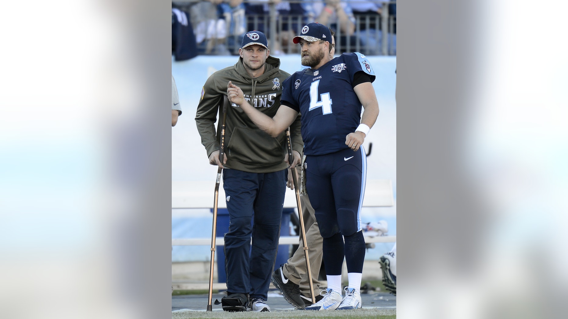 Tennessee Titans quarterback Jake Locker, left, watches from the sideline as he talks with fellow quarterback Ryan Fitzpatrick (4) in the fourth quarter of an NFL football game on Sunday, Nov. 10, 2013, in Nashville, Tenn. Locker injured his foot earlier in the game. (AP Photo/Mark Zaleski)