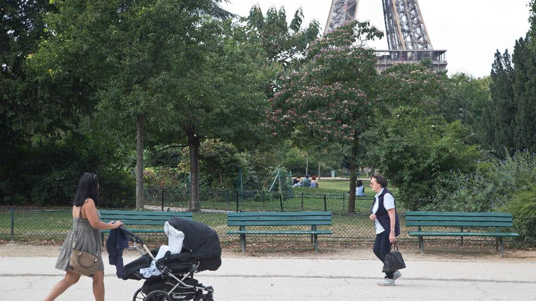 People stroll in the Champ de Mars garden near the Eiffel Tower, beside the spot where a woman was allegedly raped earlier this week, in Paris, Friday, Sept. 16, 2016. Three Algerian young men have been arrested in Paris under suspicion of raping a woman near the Eiffel Tower, according to a police official. One of the suspects chatted with her on Facebook days earlier and gave her an appointment. (AP Photo/Michel Euler)
