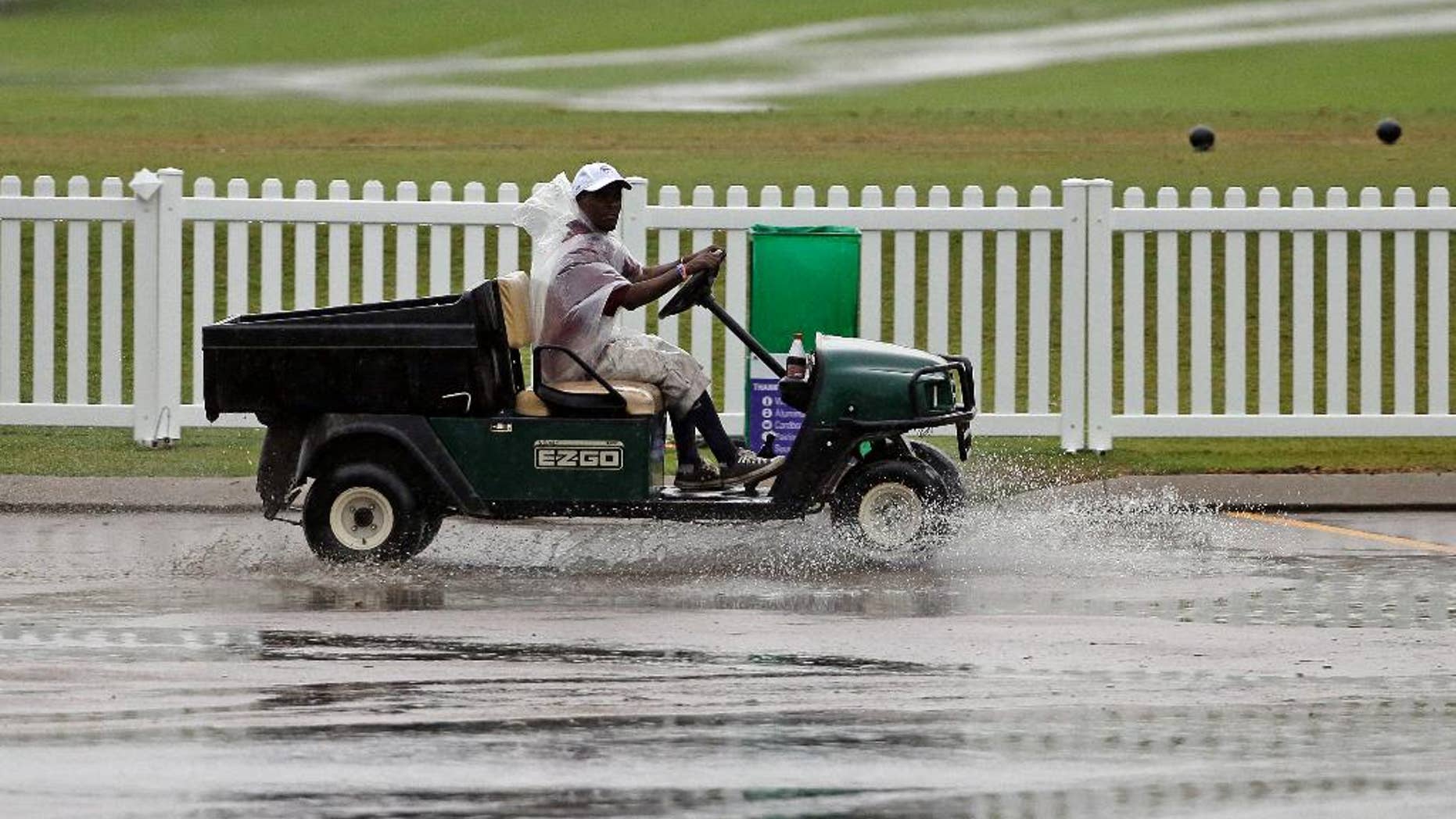 A worker drives a golf cart through standing water during a weather delay at the second round of the St. Jude Classic golf tournament Friday, June 6, 2014, in Memphis, Tenn. (AP Photo/Mark Humphrey)