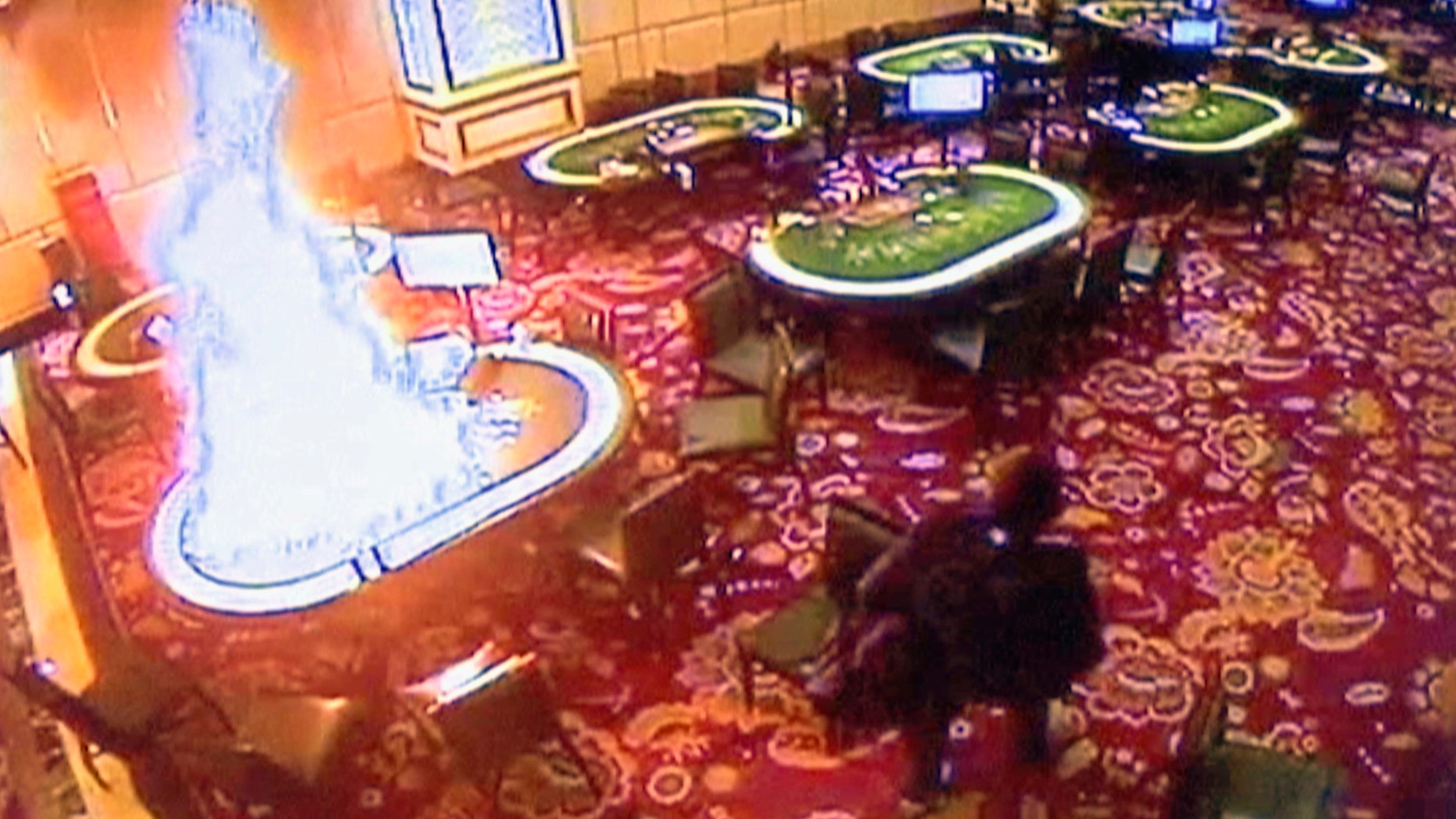 In this image made from security video released by Manila Police and Resorts World Manila on Saturday, June 3, 2017, a gunman walks away after setting fire to a gambling table in the Resorts World Manila entertainment and gambling complex in suburban Pasay city, southeast of Manila, Philippines on Friday, June 2, 2017.