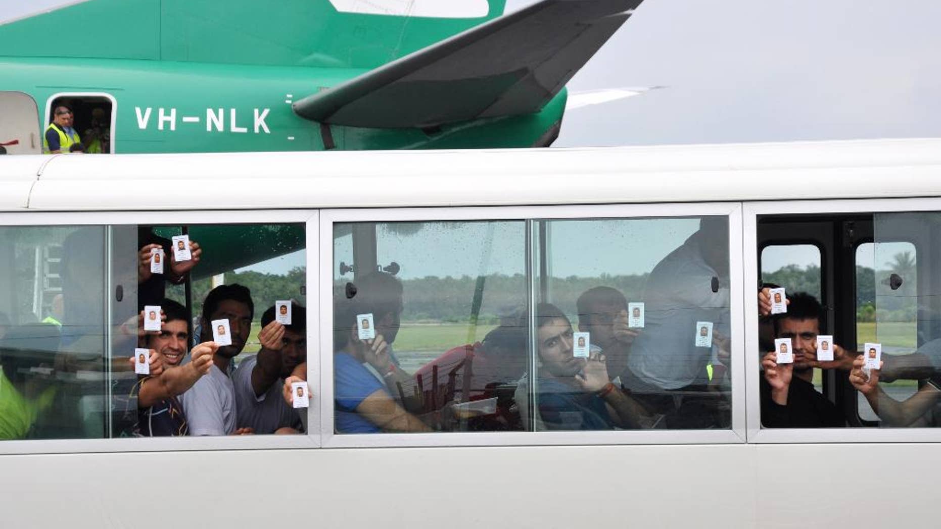 In this Aug. 2, 2013, photo, a group of asylum seekers hold up their identity after landing in Manus Island, Papua New Guinea. Papua New Guinean Prime Minister Peter O'Neill issued a statement Wednesday, Aug. 17, 2016, saying he met with Australian Immigration Minister Peter Dutton and that the two countries agreed the center will be closed. (Eoin Blackwell/AAP Image, via AP)