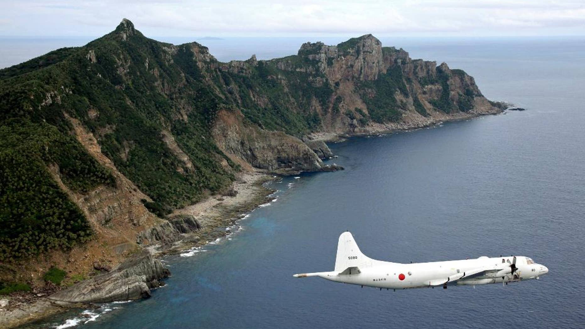 FILE - In this Oct. 13, 2011 file photo, Japan Maritime Self-Defense Force P-3C Orion surveillance plane flies over the disputed islands, called the Senkaku in Japan and Diaoyu in China, in the East China Sea. Japan protested to China on Thursday, June 9, 2016, after spotting a Chinese warship for the first time near disputed islands in the East China Sea. Japanese officials said a Chinese navy frigate was seen off the coast of the Japanese-controlled Senkaku islands, also claimed by China and called the Diaoyu islands. The ship did not violate Japan's territorial waters, and it has since left the area.(Kyodo News via AP, File) JAPAN OUT, CREDIT MANDATORY