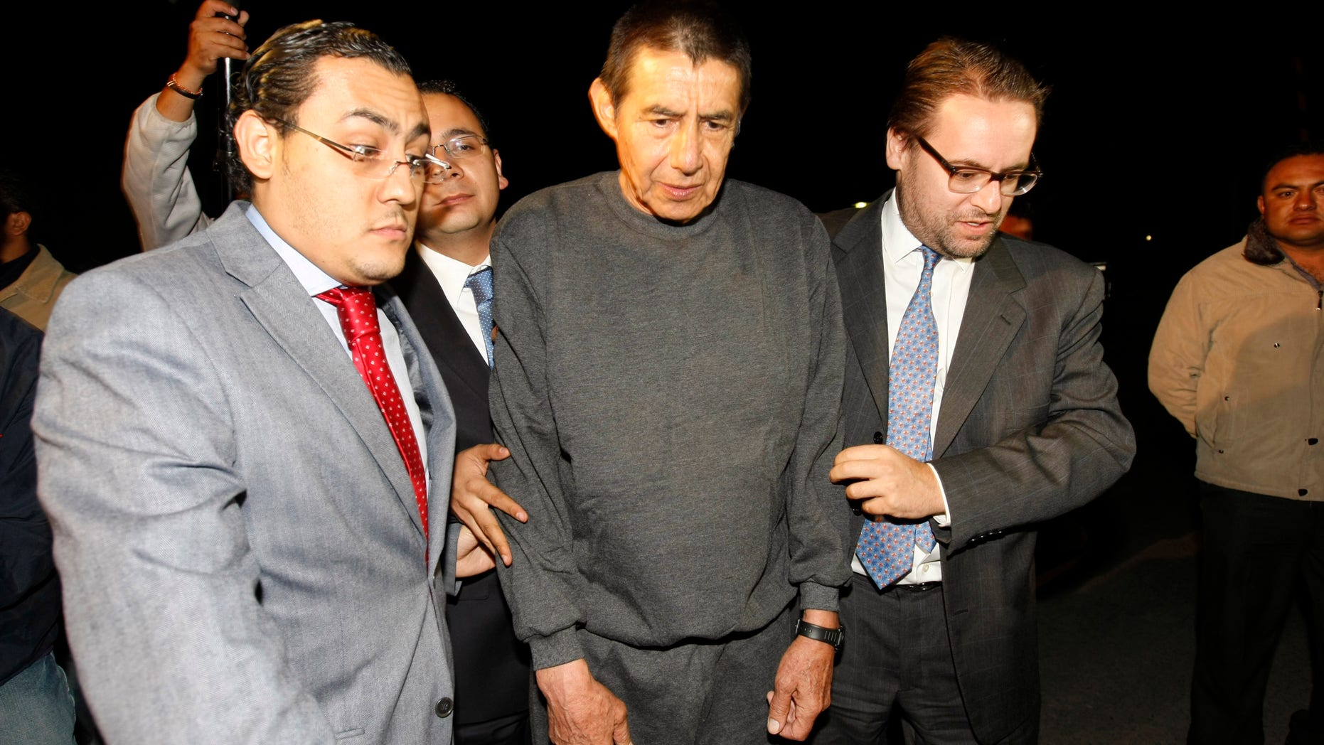 Retired Mexican Army General Tomas Angeles Dauahare, center, is escorted by unidentified members of his legal team as he leaves the Altiplano maximum security prison in Almoloya de Juarez, Mexico, Thursday, April 18, 2013. Federal prosecutors have dropped organized crime charges against Dauahare, accused of aiding a drug cartel after determining that the witness testimony was not enough to sustain their case. He had been in prison since last year, charged with protecting members of the Beltran Leyva cartel. (AP Photo)