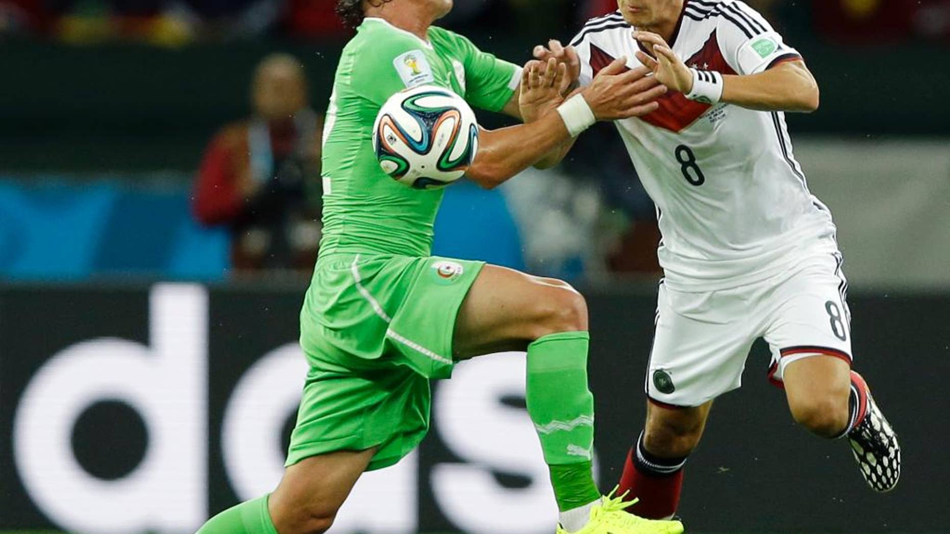 Algeria's Mehdi Mostefa, left, pushes off Germany's Mesut Ozil to stop his attack during the World Cup round of 16 soccer match between Germany and Algeria at the Estadio Beira-Rio in Porto Alegre, Brazil, Monday, June 30, 2014. (AP Photo/Kirsty Wigglesworth)