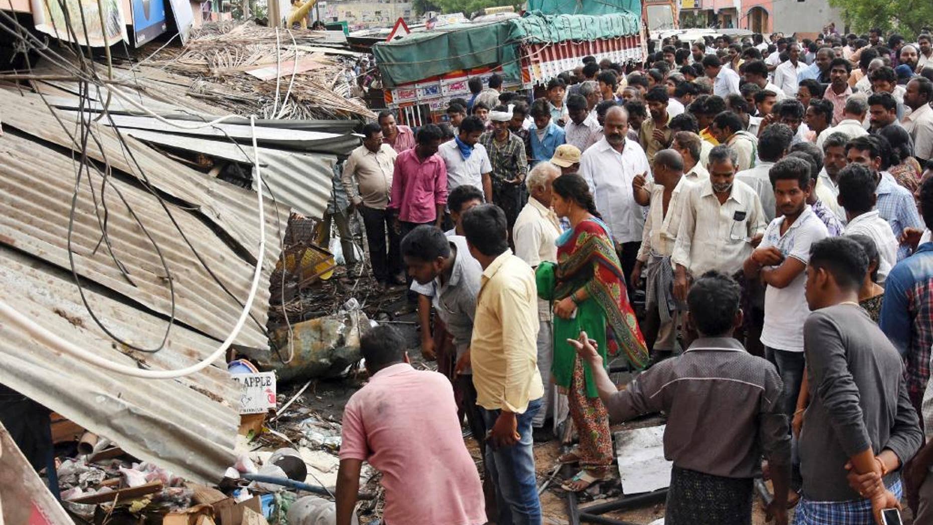 People stand at the site of an accident after a truck driver lost control and plowed into a group of protesting farmers in Yerpedu, in the southern Indian state of Andhra Pradesh, Friday, April 21, 2017. At least a dozen of those killed were electrocuted because the bus first hit an electricity pole causing high-tension wires to fall onto the crowd, police official Jaya Lakshmi said. The farmers were gathered outside the main police station protesting against illegal sand mining in their area. (AP Photo)