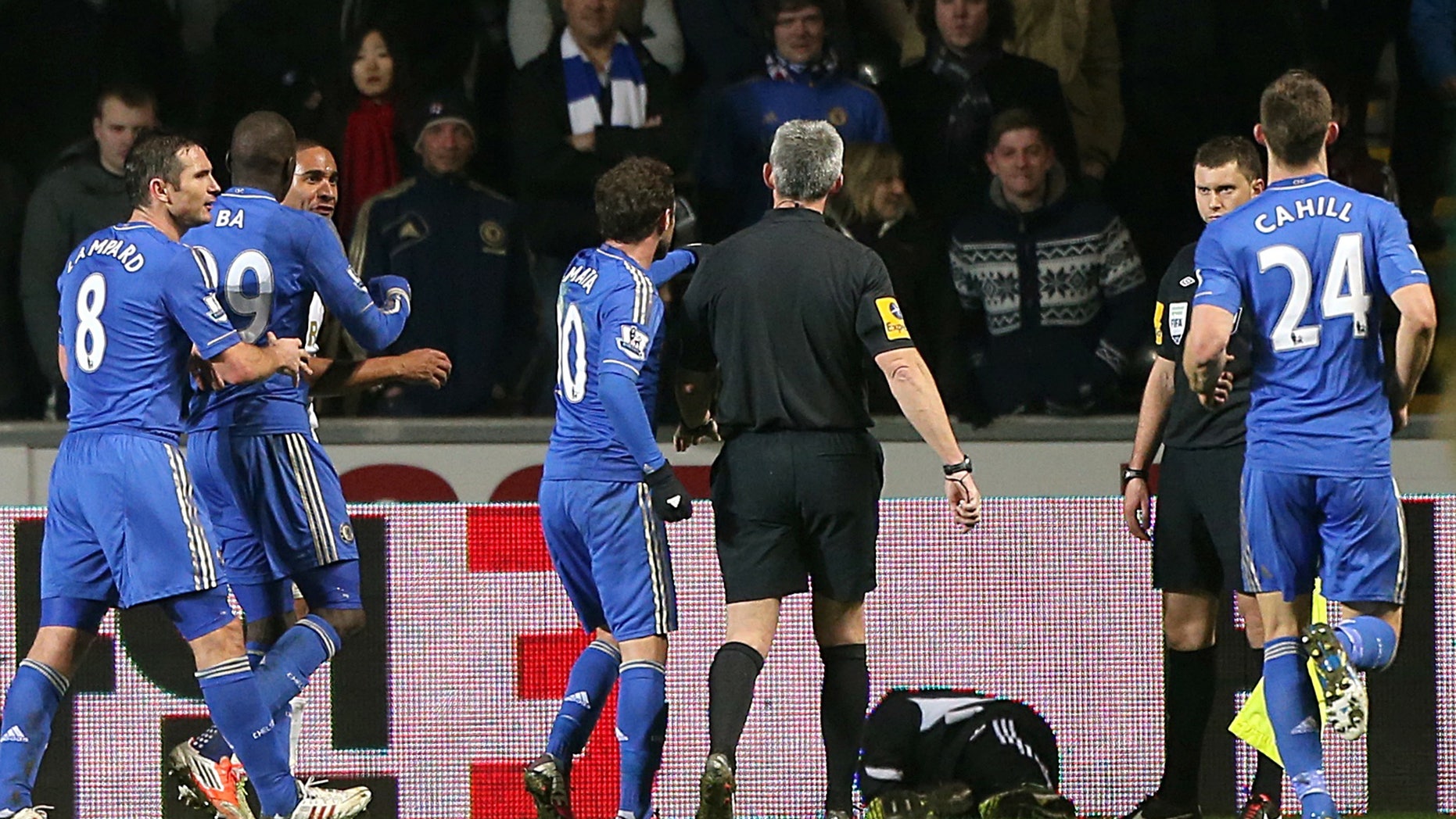A ball boy, third right, lies on the pitch following an incident Chelsea's Eden Hazard, not pictured, as referee Chris Foy, center in black, makes his way over to calm the situation during the English League Cup second leg semi-final soccer match between Chelsea and Swansea City at the Liberty Stadium, Swansea, Wales, Wednesday Jan. 23, 2013. Hazard received a red card for the incident. (AP Photo/PA, Nick Potts) UNITED KINGDOM OUT NO SALES NO ARCHIVE