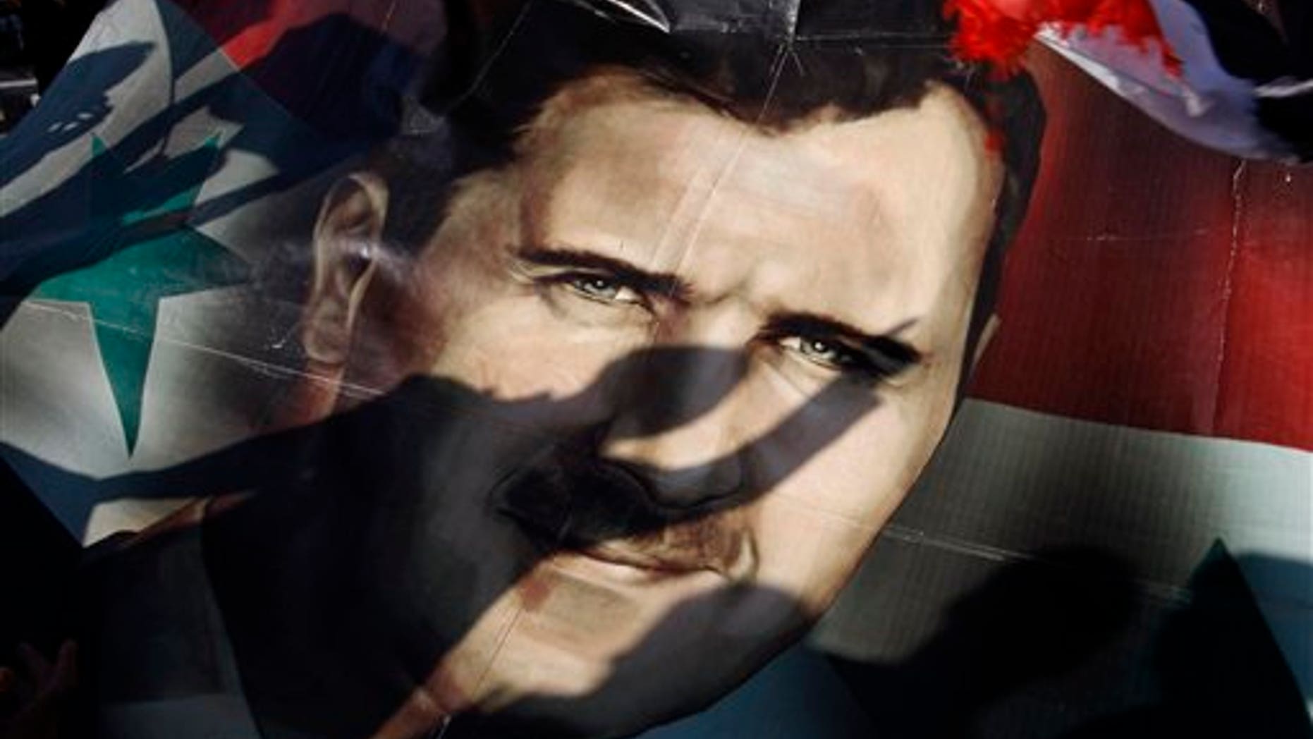 Dec. 16: Shadows of Syrians are reflected on a giant poster showing President Bashar Assad, during a supporting rally in Damascus, Syria.