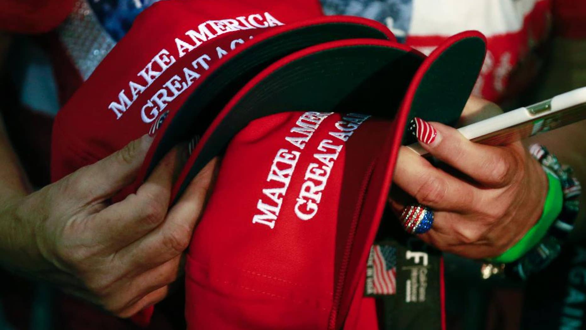 FILE - In this June 2, 2016, file photo, a woman holds hats to get them autographed by Republican presidential candidate Donald Trump during a rally in San Jose, Calif. The New York Post reported on March 19, 2017, that a Philadelphia man sued a New York City bar, claiming he was denied service for wearing such a hat. (AP Photo/Jae C. Hong, File)