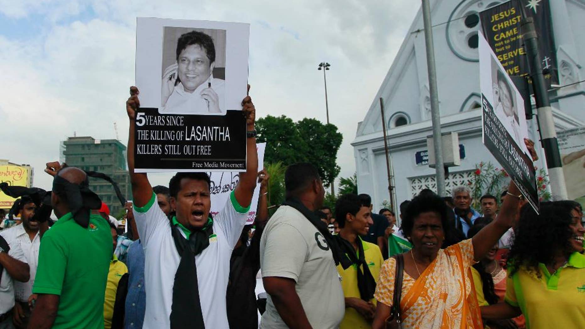 FILE- In this Jan. 28, 2014 file photo, a protestor holds a portrait of Lasantha Wickrematunge, a journalist who was killed, during a protest in Colombo, Sri Lanka. A Sri Lankan court on Thursday gave permission to police to exhume the remains of the newspaper editor killed seven years ago for a fresh investigation. (AP Photo/Eranga Jayawardena, File)