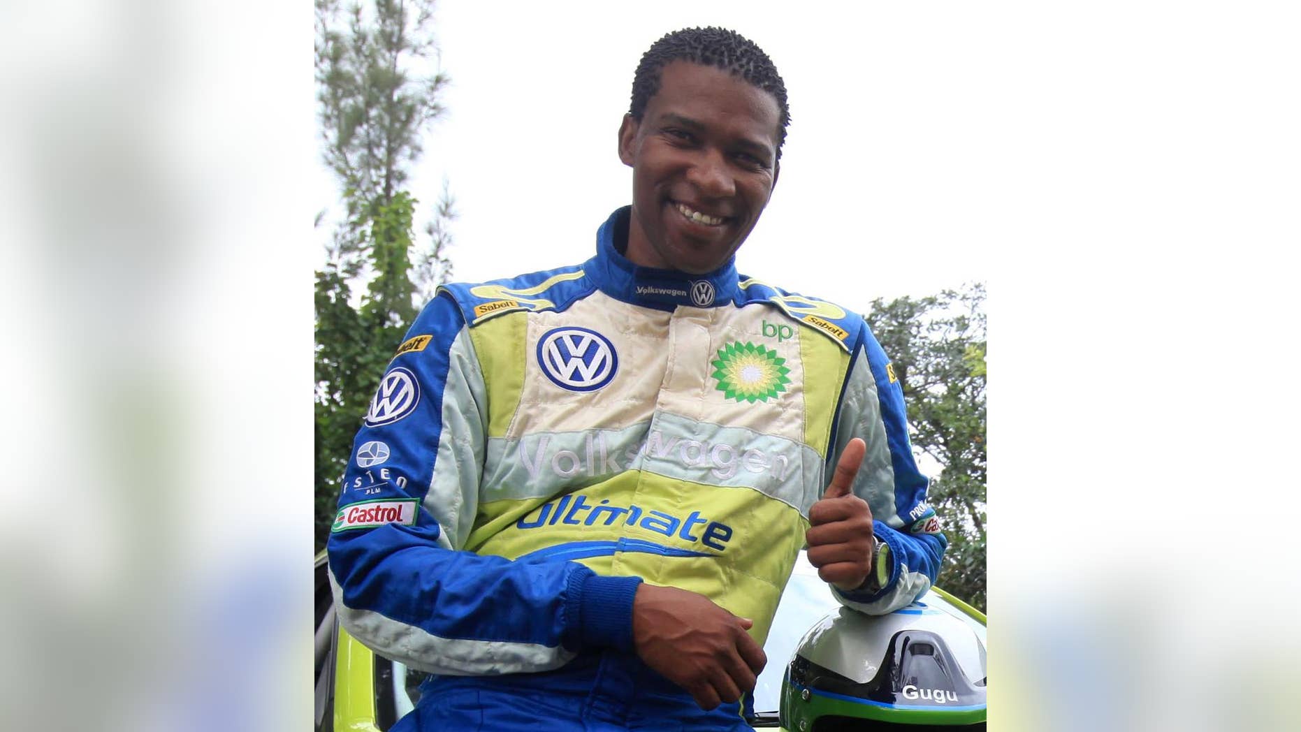 In this photo taken in 2011, South Africa rally driver Gugu Zulu gestures next to his car. A South African trying to summit Kenya's Mount Kilimanjaro to mark Mandela Day has died. A statement from the Nelson Mandela Foundation said details are "sketchy" but that it appeared Gugu Zulu had problems breathing early Monday July 18, 2016, as his group tried to reach Africa's highest peak. (AP Photo)