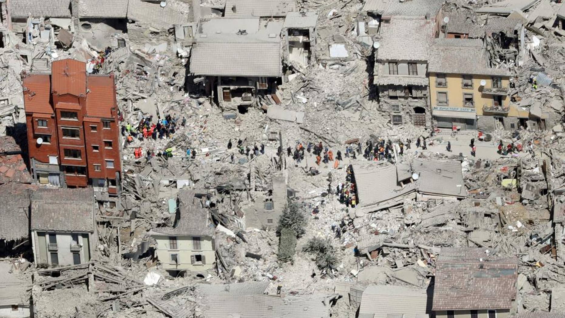 FILE - In this Wednesday, Aug. 24, 2016 file photo, an aerial photo shows the damaged buildings in the town of Amatrice, central Italy, after an earthquake. The Italian town of Amatrice, hardest hit by an earthquake last month, has filed Monday, Sept. 12, 2016, a criminal complaint denouncing French satirical weekly Charlie Hebdo for a cartoon depicting victims in layers of lasagna. (AP Photo/Gregorio Borgia, File)