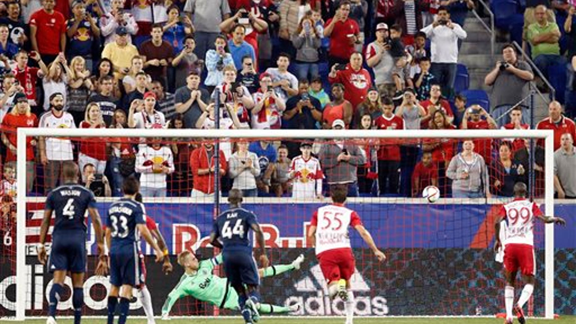 Vancouver Whitecaps FC goalkeeper David Ousted, center left, watches the ball after he deflected a penalty kick by New York Red Bulls forward Bradley Wright-Phillips, right, during the second half of an MLS soccer match, Saturday, June 20, 2015, in Harrison, N.J. Ousted denied Wright-Phillips on two penalty kicks and the Whitecaps won 2-1. (AP Photo/Julio Cortez)