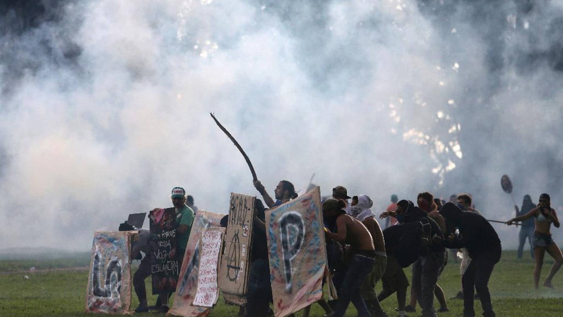 Protesters shield themselves as police fire tear gas outside Congress, where senators planned to vote on a spending cap bill and the lower Chamber of Deputies was considering controversial anti-corruption legislation, in Brasilia, Brazil, Tuesday, Nov. 29, 2016. Brazil, home to Latin America’s largest economy, is suffering its worst recession in decades. (AP Photo/Eraldo Peres)
