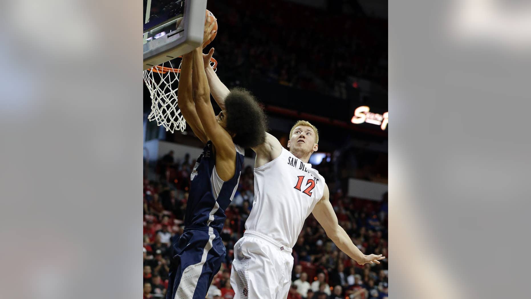 San Diego State's James Johnson (12) covers a shot from Utah State's Jalen Moore during the second half of an NCAA college basketball game in the quarterfinals of the Mountain West Conference tournament on Thursday, March 13, 2014, in Las Vegas. San Diego State defeated Utah State 73-39. (AP Photo/Isaac Brekken)