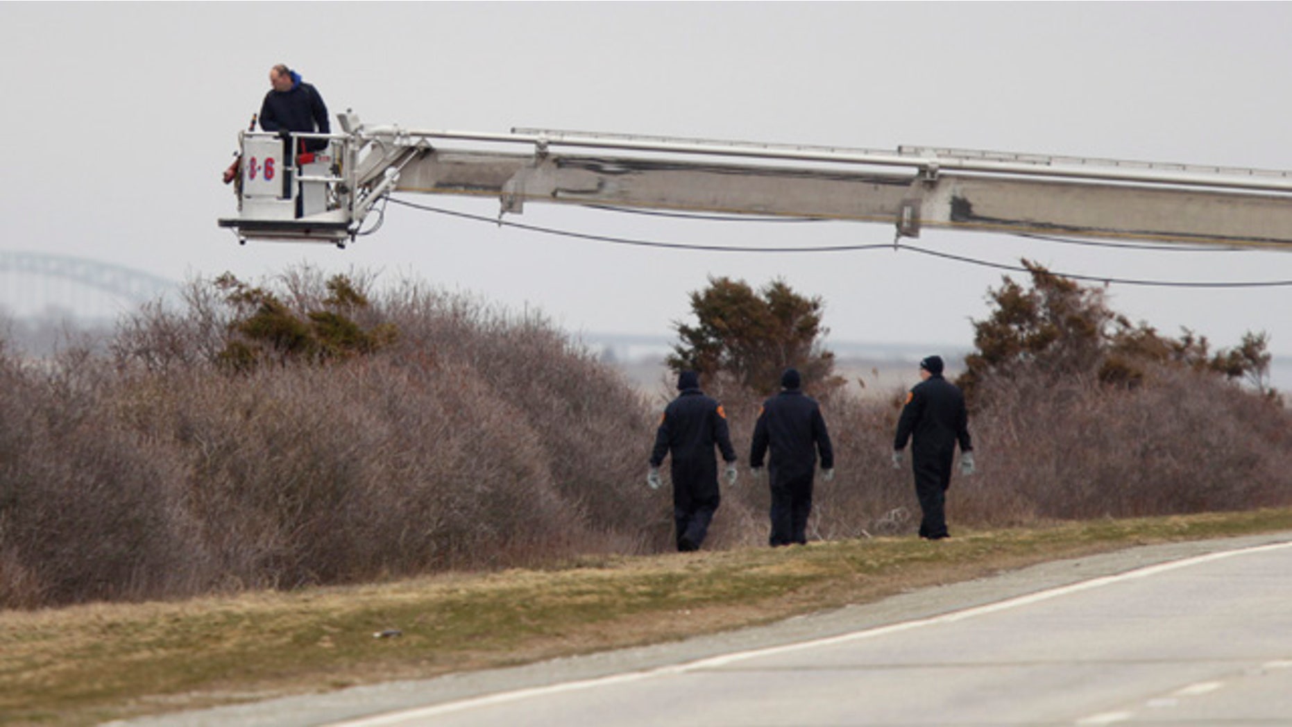 April 4, 2011: Police aided by a man in a fire department bucket ladder search in the brush near Oak Beach, N.Y. Three sets of human remains were found Monday, bringing to eight the total number of bodies found in the area since December.