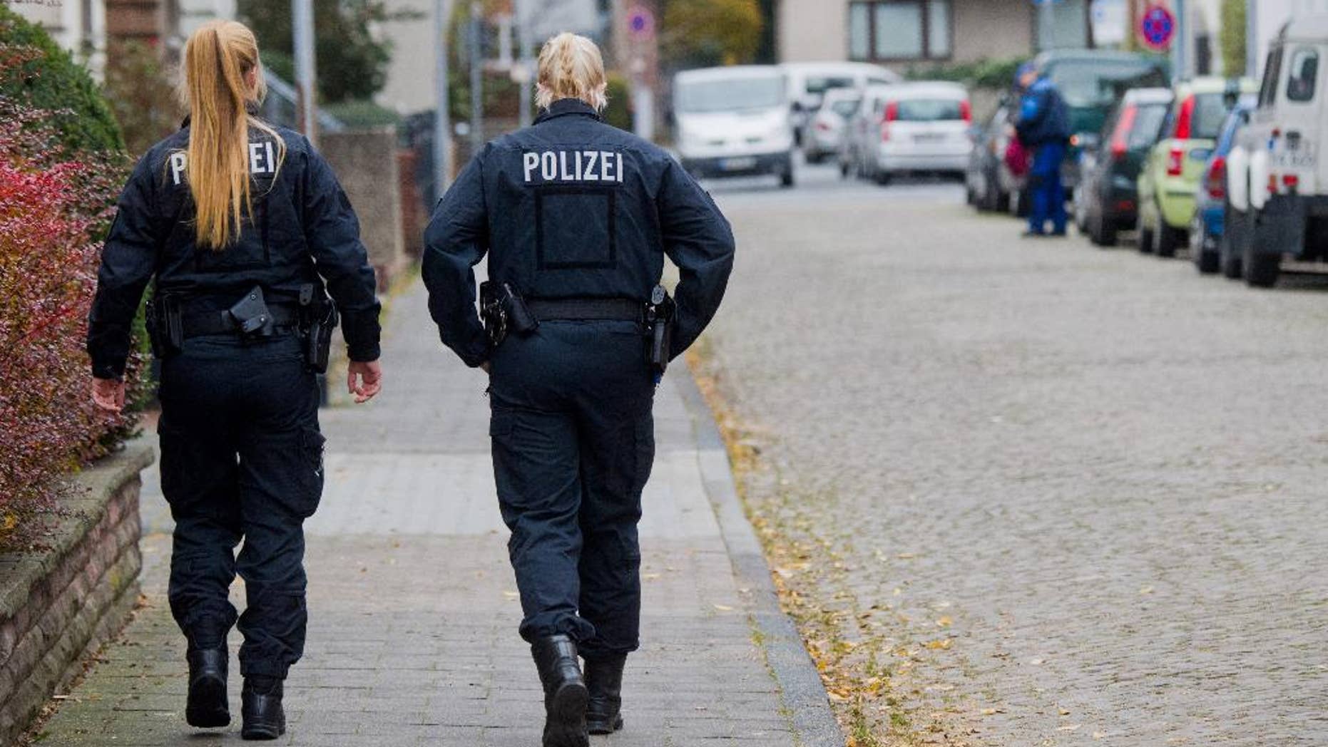 Policewomen walk along a street in Hameln, Germany, Monday Nov. 21, 2016. A woman was seriously injured when she was dragged Sunday through the streets of the northern German town behind a car with a cord tied around her neck. Her ex-partner later turned himself in to authorities, prosecutors said Monday, (Julian Stratenschulte/dpa via AP)