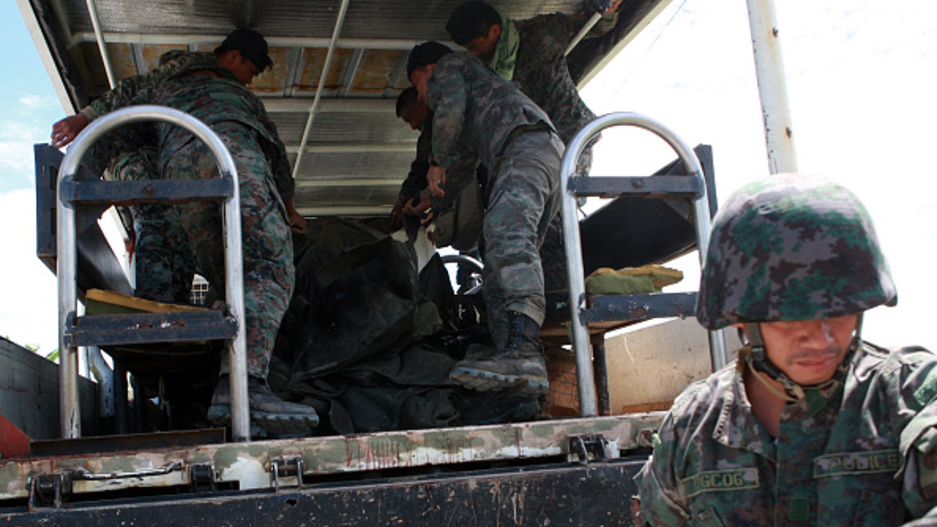 MAGUINDANAO PROVINCE, PHILIPPINES - JANUARY 26: Policemen load into a truck the body of their comrade during a retrieval operation on January 26, 2015 in Mamasapano, Maguindanao Province, Philippines. Dozens of elite policemen were killed after a clash with a Muslim rebel group. Lawmen would suppose serve the arrest warrants on January 25, 2015 for criminals led by Malaysian bomb maker Zulkifli bin Hir, known in military and police officials as Marwan, when the group clashed with the guerillas under Commander Guiawan of Bangsamoro Islamic Freedom Fighters, a breakaway group of the Moro Islamic Liberation, the countrys largest rebel group engaged in peace talks with Manila. The death toll of government fatalities in the fierce firefight reached fifty. (Photo by Jeoffrey Maitem/Getty Images)