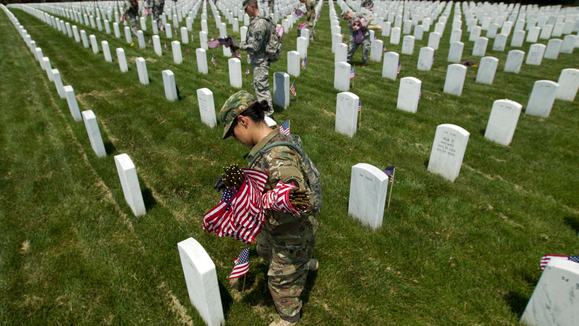 Members of the Old Guard with the Washington Memorial in the back, place flags in front of every headstone at Arlington National Cemetery in Arlington, Va., Thursday, May 26, 2016. Soldiers were to place nearly a quarter of a million American flags at the cemetery as part of a Memorial Day tradition. ( AP Photo/Jose Luis Magana)