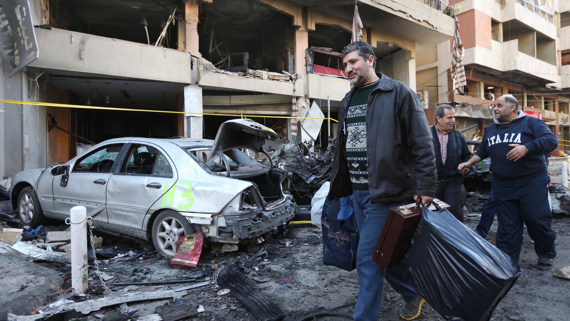 A Lebanese man carries his belongings as he leaves his damaged house at the site of an explosion in a stronghold of the Lebanese Shiite group Hezbollah in Beirut, Lebanon, Friday, Jan. 3, 2014. An explosion tore through a crowded commercial street Thursday in a south Beirut neighborhood that is bastion of support for the Shiite group Hezbollah, killing several people, setting cars ablaze and sending a column of black smoke above the Beirut skyline. (AP Photo/Hussein Malla)