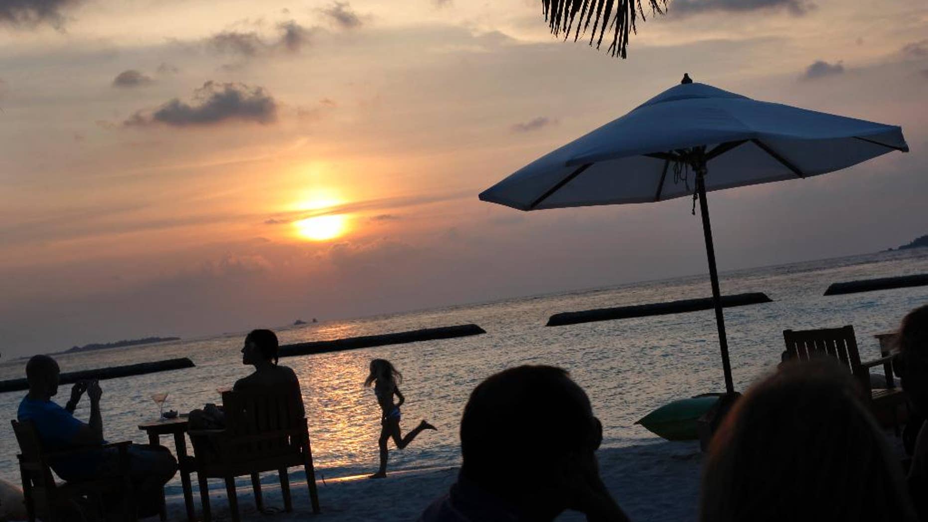 FILE - In this Feb. 16, 2012, file photo, foreign tourists gather at a sand-bar to watch sunset at Kurumba resort in Male atoll, Maldives. Maldives, best known for its palm-fringed beaches and luxury resorts, but riven by political power struggles since becoming a democracy only seven years ago. An explosion in September 2015 aboard the presidential boat set the Maldives on course for its latest political shakeup, with the Vice President Ahmed Adeeb arrested over the weekend on suspicion of high treason for allegedly plotting to assassinate the country’s leader. (AP Photo/Gemunu Amarasinghe, File)