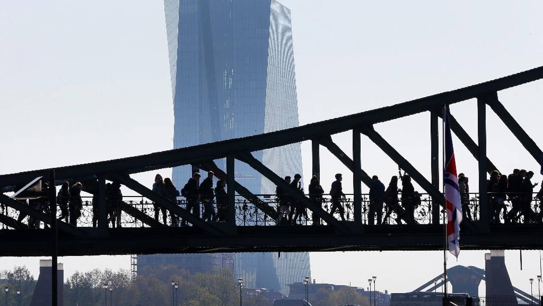 People walk over a bridge near the European Central Bank (background) in Frankfurt, Germany, Monday, May 2, 2016. (AP Photo/Michael Probst)