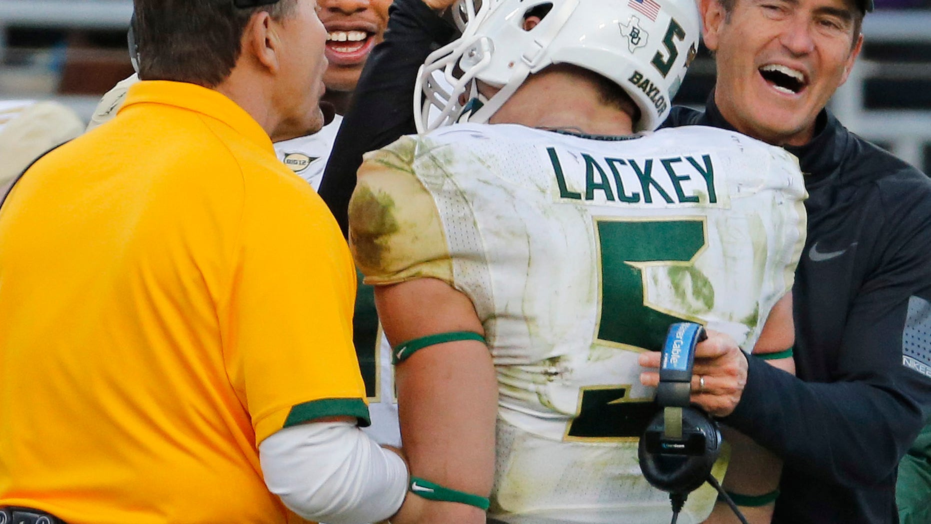Baylor linebacker Eddie Lackey (5) gets a hug from head coach Art Briles, right, and defensive coordinator Phil Bennett, left, after returning an interception for a touchdown in the third quarter of a 41-38 win over TCU in an NCAA college football game in Fort Worth, Texas, Saturday, Nov. 30, 2013. (AP Photo/Dallas Morning News, Louis DeLuca) MANDATORY CREDIT; NO SALES; MAGAZINES OUT; TV OUT; INTERNET USE BY AP MEMBERS ONLY