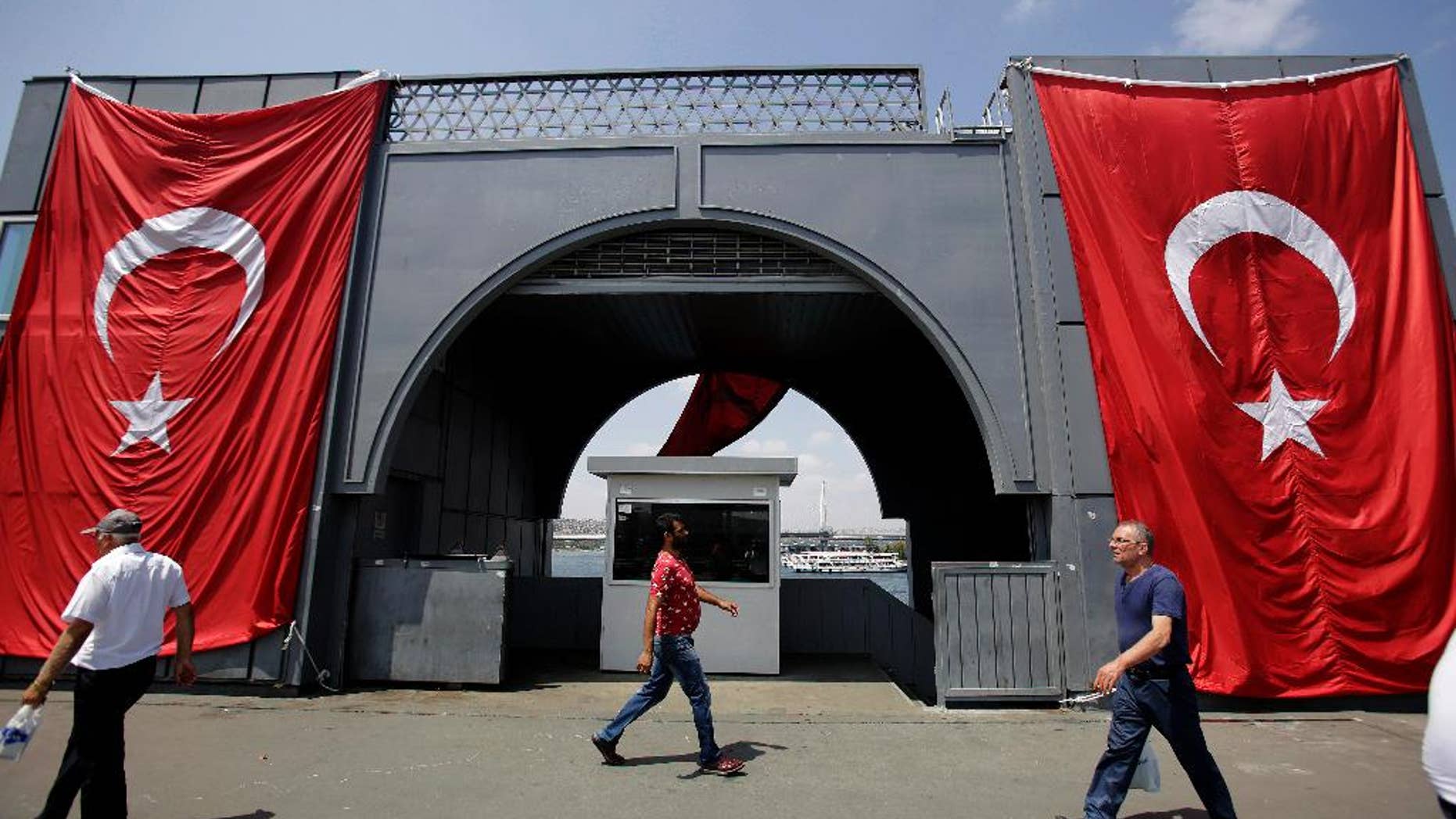 Men walk at the Galata bridge past two Turkey flags, in Istanbul, on Tuesday, Aug. 2, 2016. Turkey's justice minister has sent a document to the United States seeking the arrest of cleric Fethullah Gulen, who lives in self-imposed exile in Pennsylvania and who Ankara accuses of instigating an attempted coup on July 15. (AP Photo/Petros Karadjias)