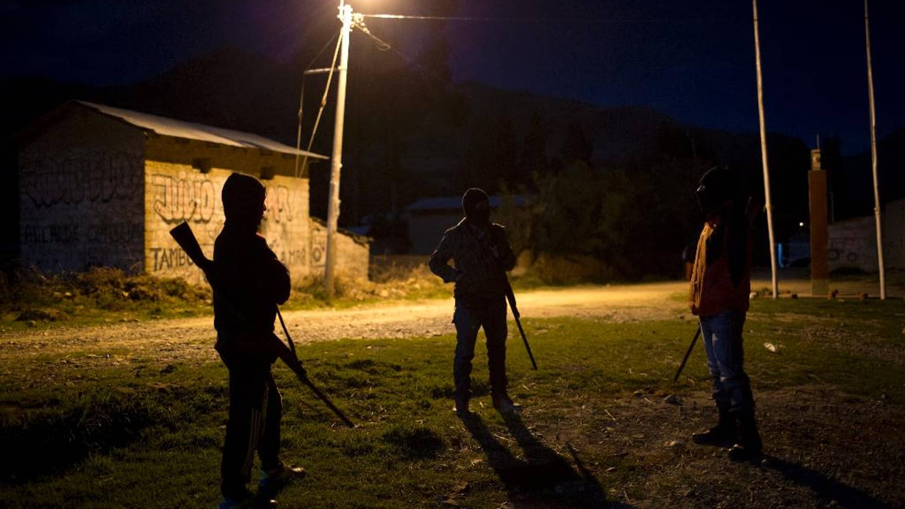 FILE - In this Nov. 25, 2015 file photo, members of a citizen's self-defense force stand guard in front of the health center where forensic anthropologists prepare the coffins with the exhumed remains of 34 people slain in 1992 by Shining Path guerrillas, in Valle Esmeralda de Huayao, Peru. The U.S. government sanctioned three leaders of Peru’s Shining Path guerrilla movement Tuesday, Nov. 22, 2016, whom it says “actively engaged in terrorism” as part of their mission to overthrow the Peruvian government. (AP Photo/Rodrigo Abd, File)