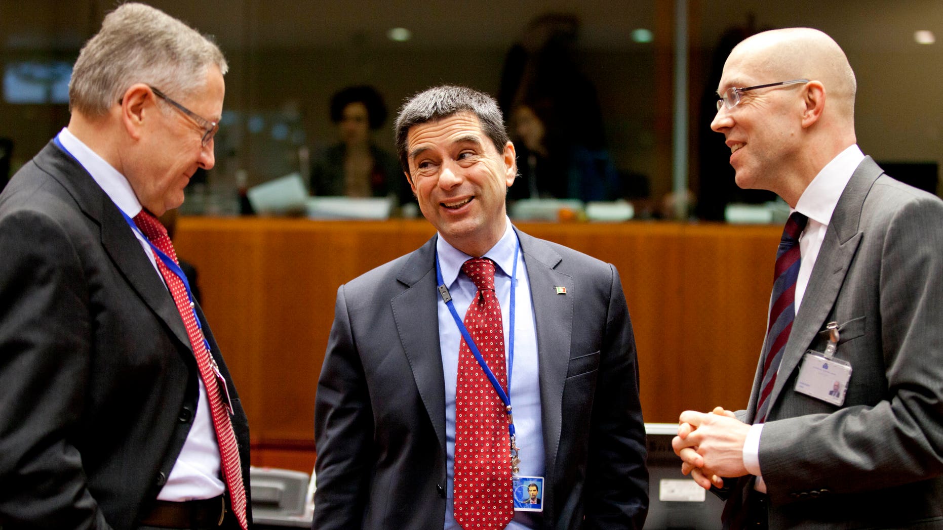 CEO of the European Financial Stability Facility, Klaus Regling, left, and member of the board of the ECB Joerg Asmussen, right, speak with Portugal's Finance Minister Vitor Gaspar during a meeting of EU finance ministers at the EU Council building in Brussels on Tuesday, Jan. 22, 2013. Eleven eurozone countries seeking to unilaterally implement a financial transaction tax are expected Tuesday to receive the blessing of other European Union countries, bringing the once-controversial project one step closer to reality. (AP Photo/Virginia Mayo)