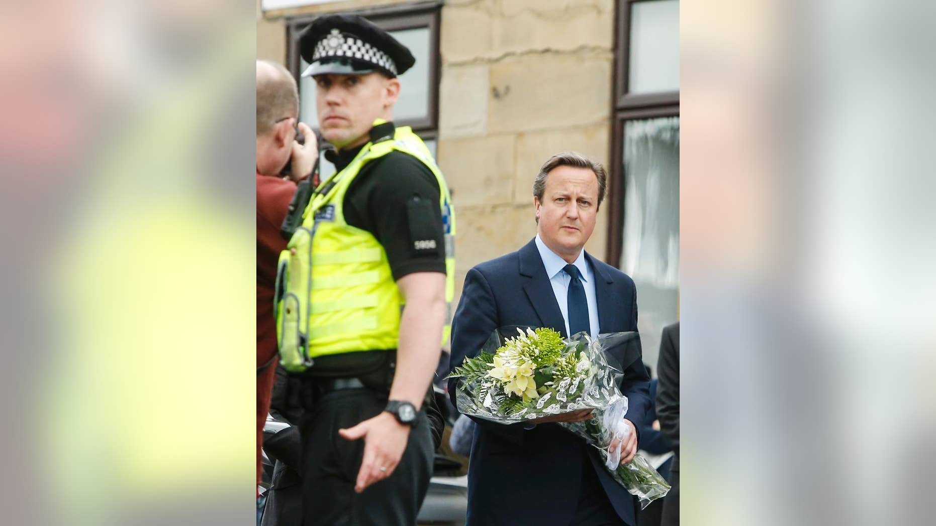 Britain's Prime Minister David Cameron prepares to lay a floral tribute in Birstall, northern England, for Jo Cox, the 41-year-old British Member of Parliament shot to death in northern England, Friday June 17, 2016. The mother of two young children was shot to death Thursday afternoon in her constituency near Leeds. A 52-year-old man has been arrested but has not been charged. (Danny Lawson/PA via AP) UNITED KINGDOM OUT