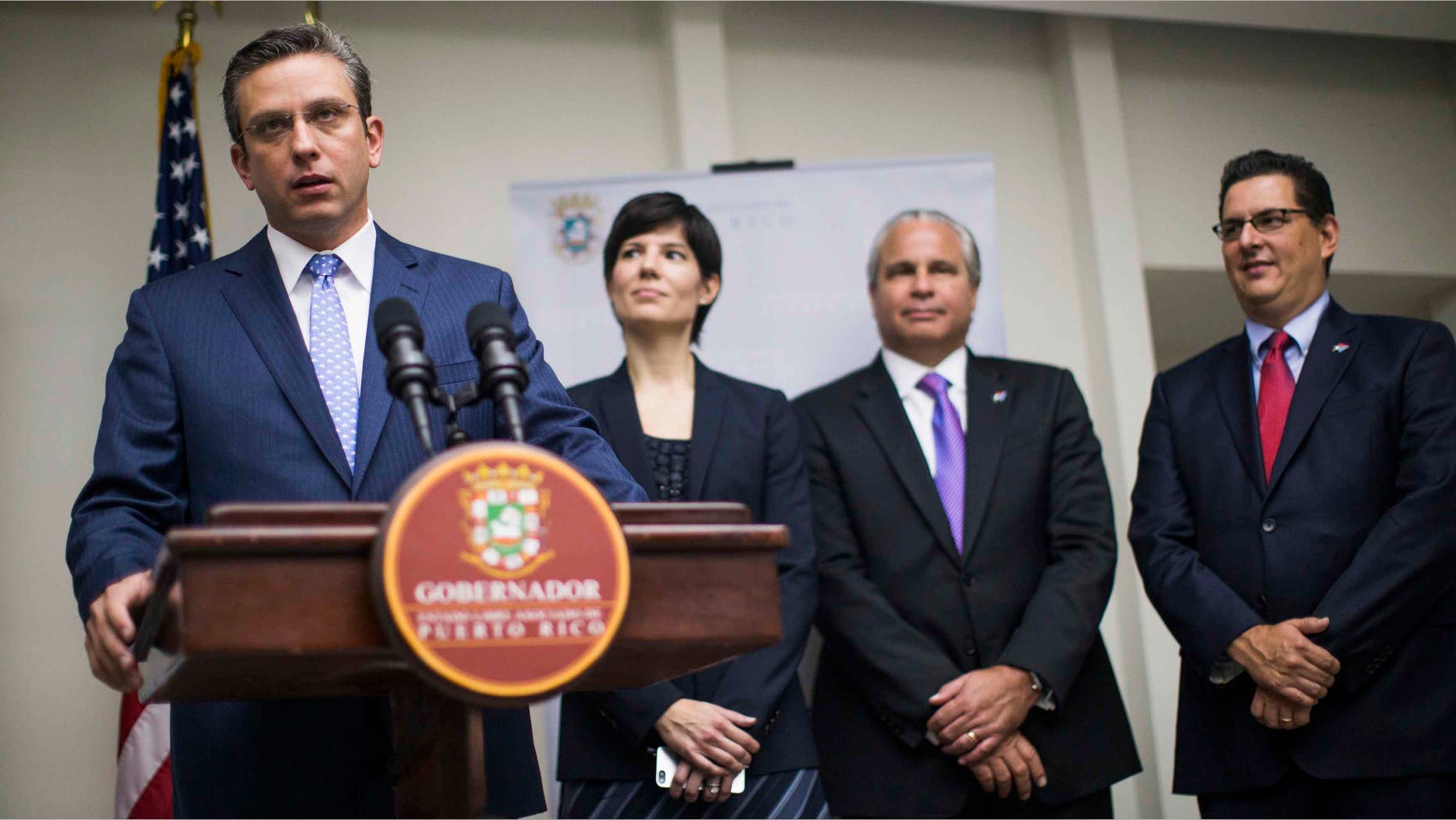 SAN JUAN, PUERTO RICO - NOVEMBER 14: Governor Alejandro Garcâa Padilla announces a 200 million dollar expansion of pharmaceutical operations of Eli Lilly in Puerto Rico at the Governor's Mansionon November 14, 2013 in San Juan, Puerto Rico, he was joined by (L-R) Chief of Staff Ingrid Vila, Secretary of Economic Development Alberto Baco, and Executive Director of the Puerto Rican Development Bank Antonio Medina Comas.The island-territory of the United States is on the brink of a debt crisis as lending has skyrocketed in the last decade with the government issuing municipal bonds. Since the tax exemption for american manufacturing companies expired in 2006 Mr. Garcâa Padilla said jobs in that sector have dropped from around 170,000 to about 80,000. (Photo by Christopher Gregory/Getty Images)
