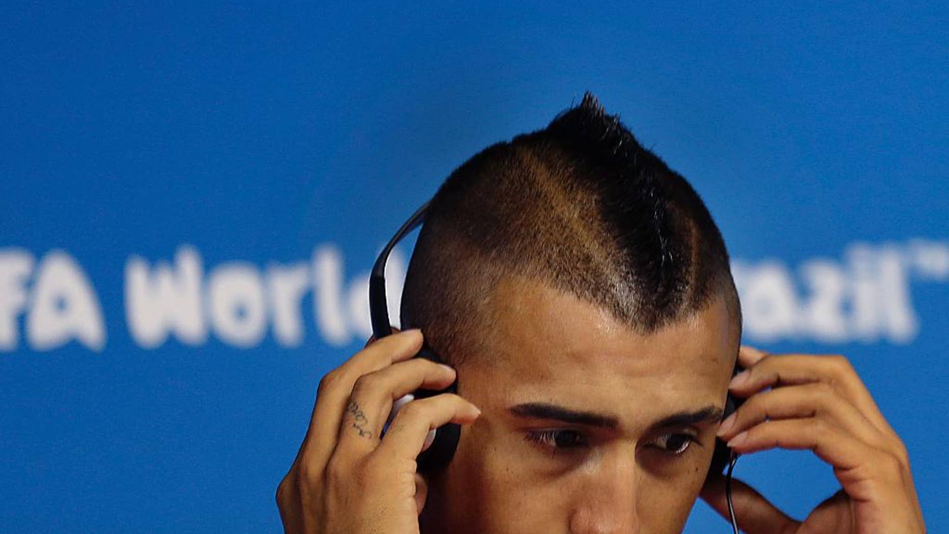El jugador de Chile, Arturo Vidal, se ajusta los audífonos en una conferencia de prensa el domingo, 22 de junio de 2014, en Sao Paulo, Brasil. (AP Photo/Wong Maye-E)