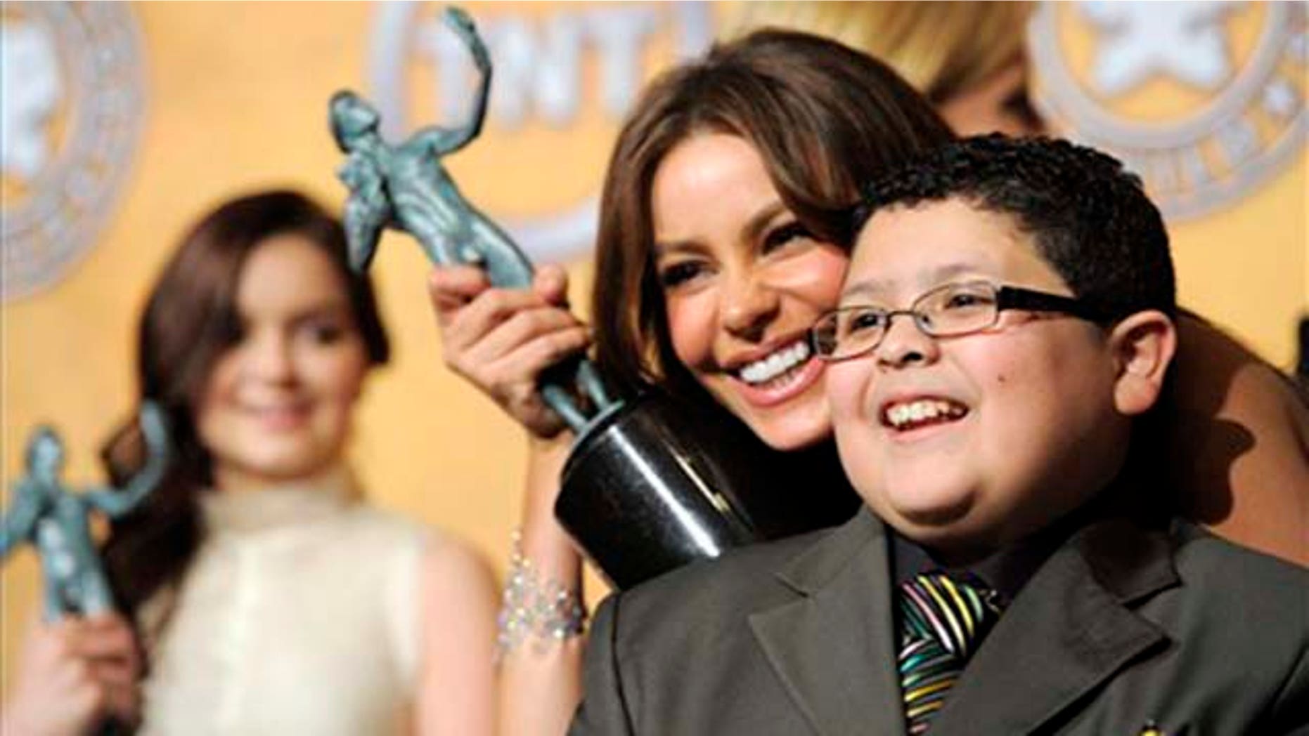 As Ariel Winter looks on, left, Sofia Vergara and Rico Rodriguez pose together with their best comedy series trophies for "Modern Family" at the 17th Annual Screen Actors Guild Awards on Sunday, Jan. 30, 2011 in Los Angeles. (AP Photo/Chris Pizzello)