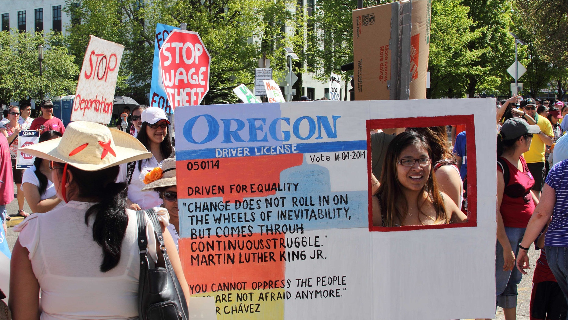 FILE - In this May 1, 2014 file photo, Nathalie Marquez holds a sign modeled after an Oregon drivers license at the Capitol, in Salem, Ore. As President Obama moves toward taking action to allow millions of people in the country illegally to stay and possibly work, the outcome of a little-noticed ballot measure in deep-blue Oregon serves as a warning to him and his party on the volatility of the immigration issue. (AP Photo/Chad Garland, file)