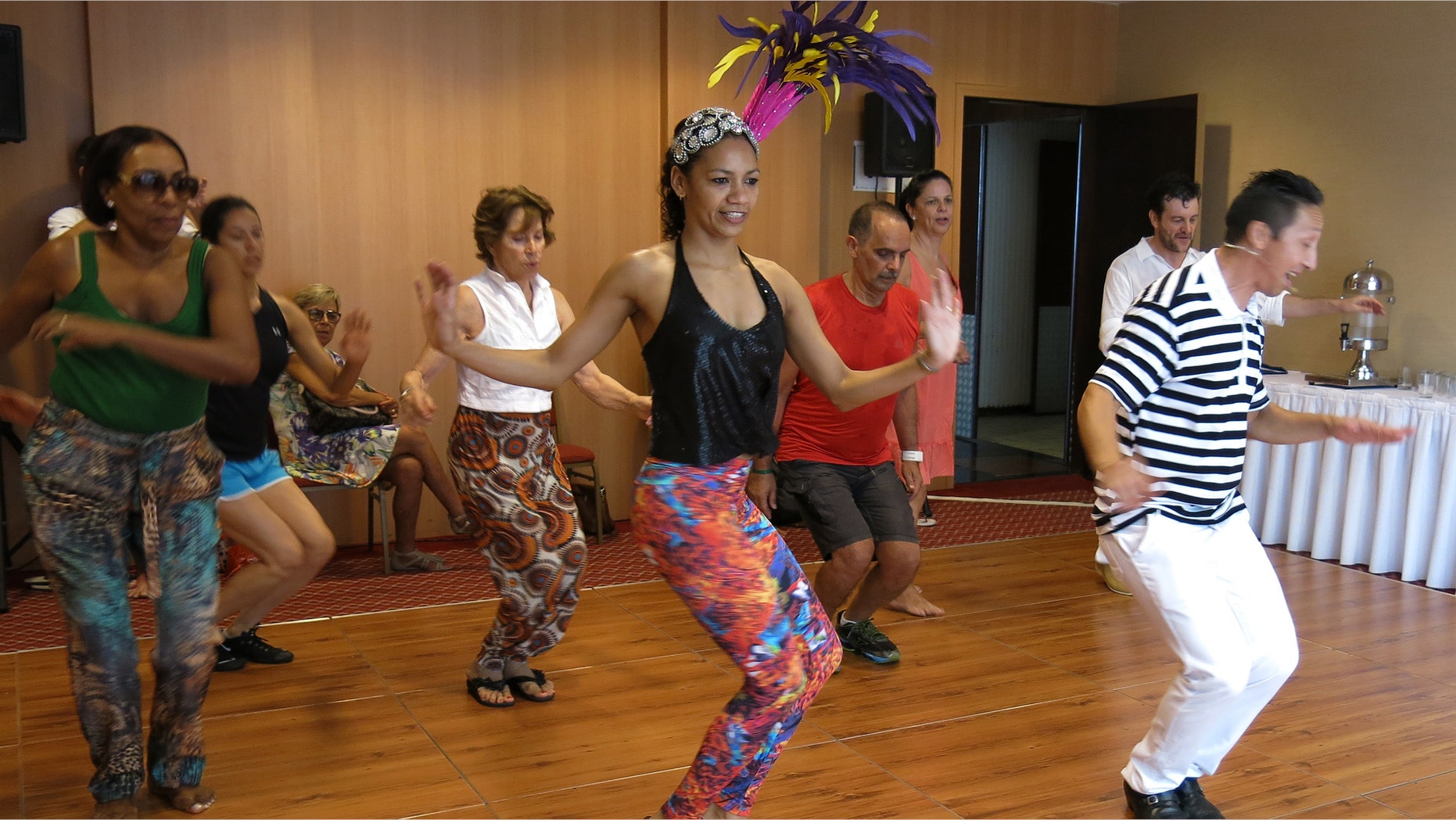 Nete Vieira, center, and her husband Naldi, right, teach samba to foreigners in Rio de Janeiro, Sunday, Feb. 15, 2015. There is a self-deprecating phrase Brazilians with poor dancing skills use to explain their awkwardness at the parades during Carnival: I samba like a foreigner. But even foreigners visiting Brazil for Carnival celebrations can learn a few basic moves thanks to the patience of dancing duo Nete Vieira and her husband Naldi. They teach the basics of rhythmic bouncing, marching and arm waving that will help newcomers have fun, and feel less intimidated, while joining the raucous parties that crowd the streets of Rio de Janeiro. (AP Photo/Adriana Gomez)