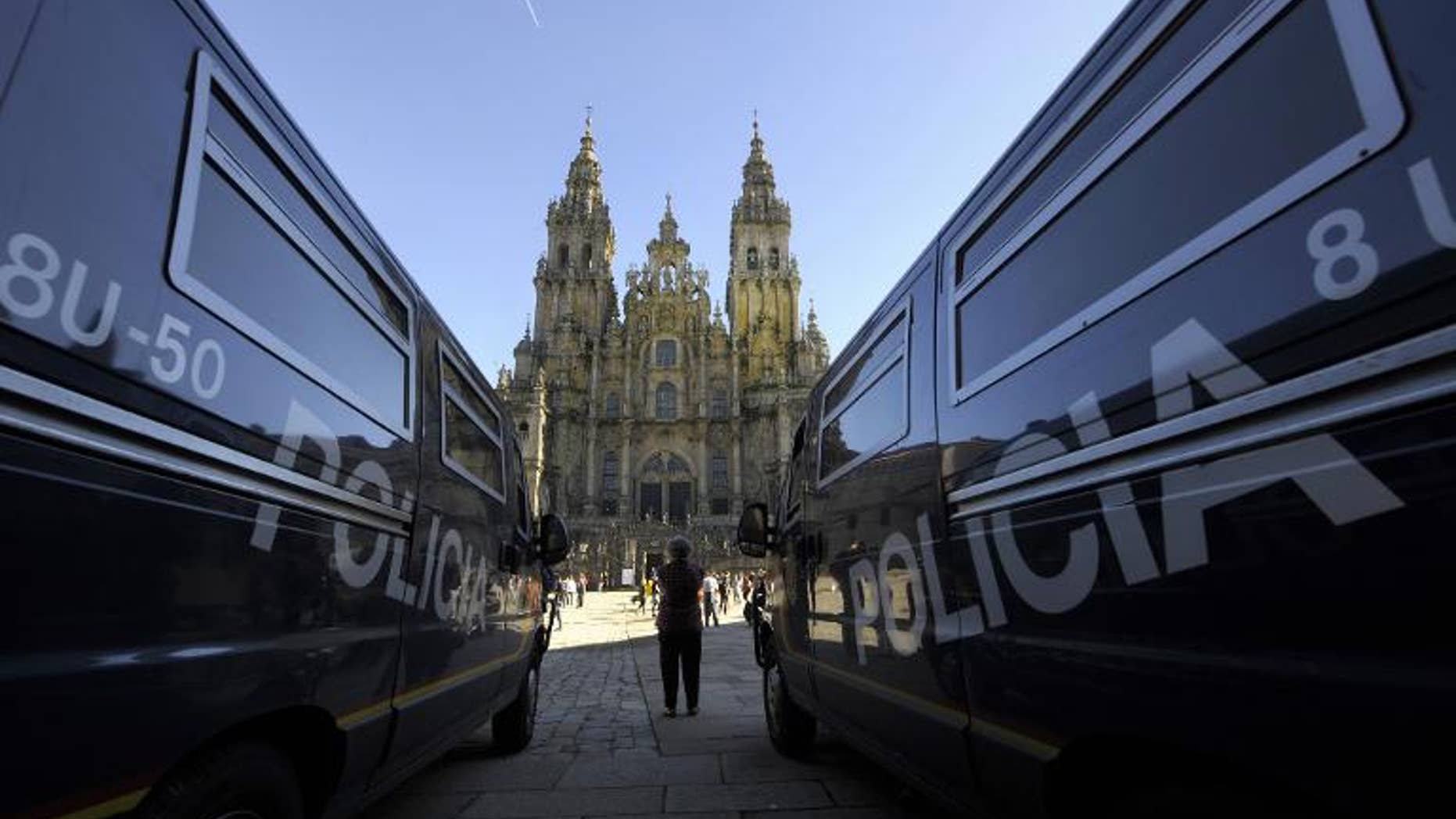 A woman stands between two police vans parked at the Obradoiro Square, in front of the Santiago de Compostela Cathedral, on November 4, 2010