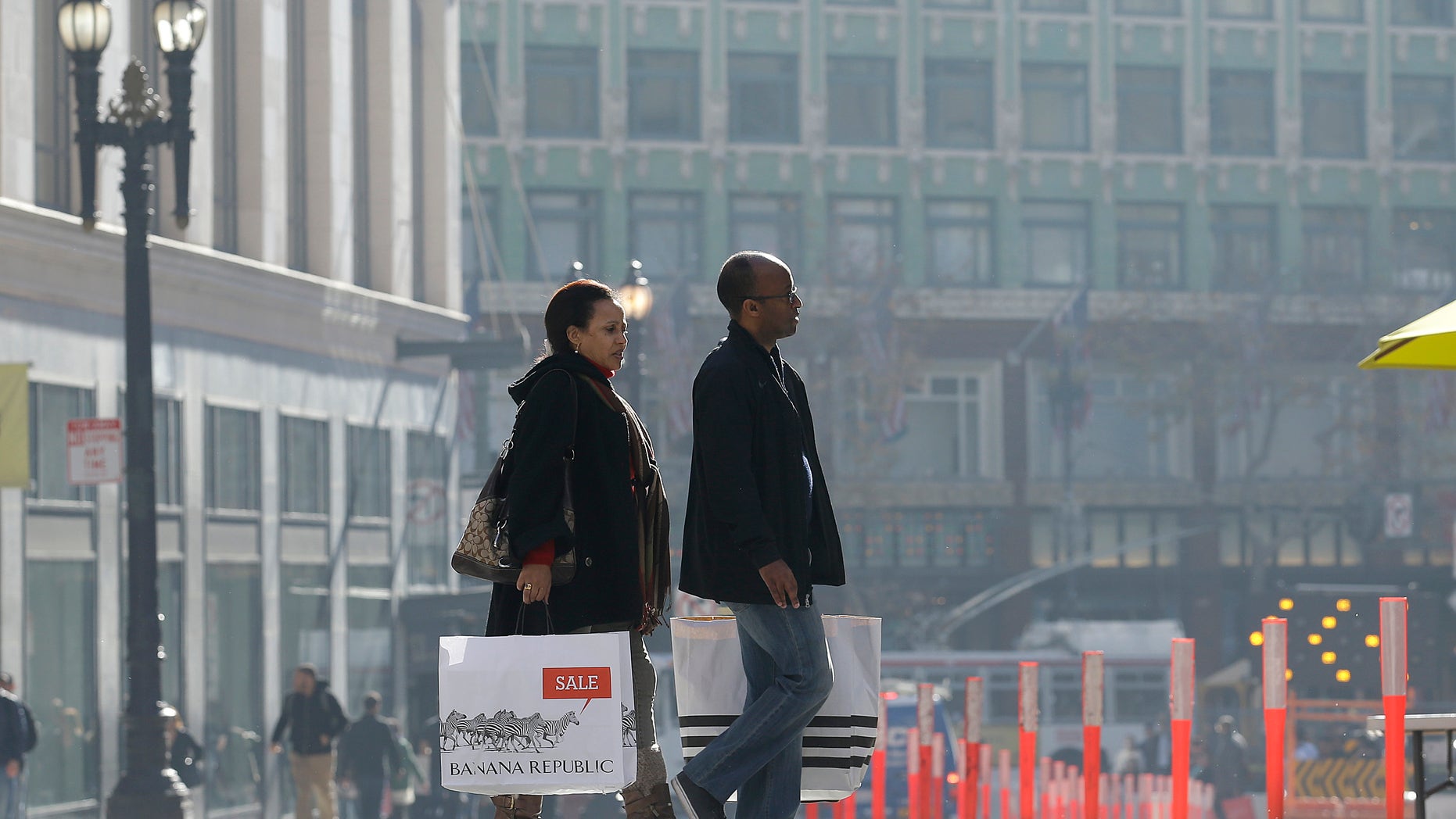 FILE - In this Tuesday, Dec. 24, 2013, file photo, a man and woman carry shopping bags as they cross the street in San Francisco. The Commerce Department reports how much consumers spent and earned in December. on Friday, Jan. 31, 2014. (AP Photo/Jeff Chiu)