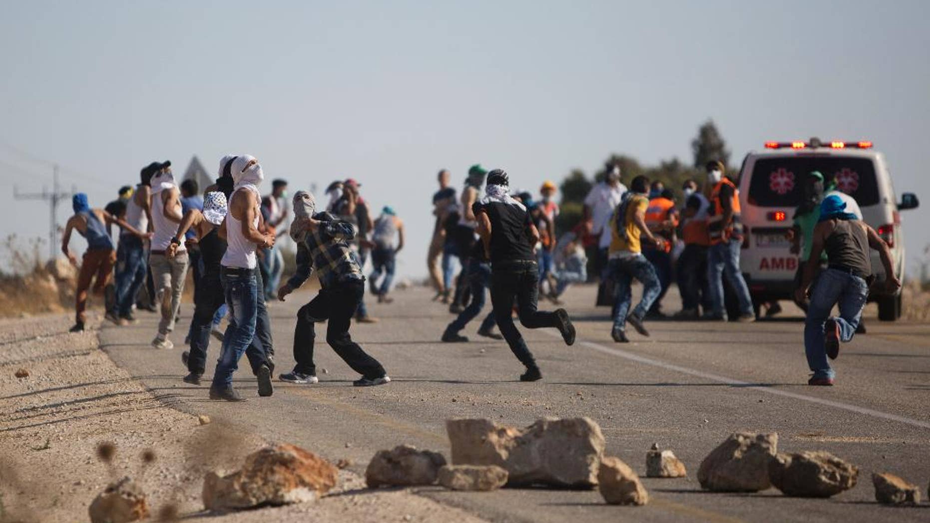Palestinians run for cover from tear gas fired by Israeli security forces during clashes that occurred after the funeral of Palestinian Saed Dawabsheh, 32, in the West Bank village of Duma near Nablus on Saturday, Aug. 8, 2015. The father of a Palestinian toddler killed in a July 31 firebomb attack blamed on Jewish extremists has died of wounds sustained in the same incident, his family said Saturday. His 18-month-old toddler perished in the flames, while his 4-year-old brother and parents were seriously hurt. (AP Photo/Majdi Mohammed)