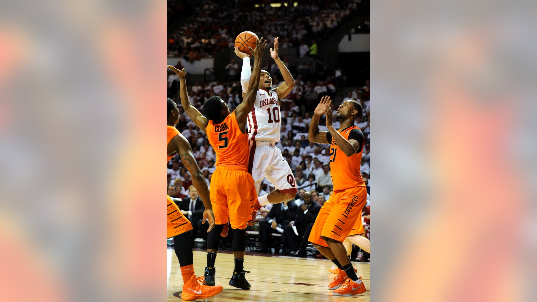 Oklahoma guard Jordan Woodard, center, takes a shot over Oklahoma State guard Stevie Clark, left, and Oklahoma State forward Kamari Murphy, right, during the second half of an NCAA college basketball game in Norman, Okla., Monday, Jan. 27, 2014. Woodard scored 18 points in the 88-76 win over rival Oklahoma State. (AP Photo/Brody Schmidt)