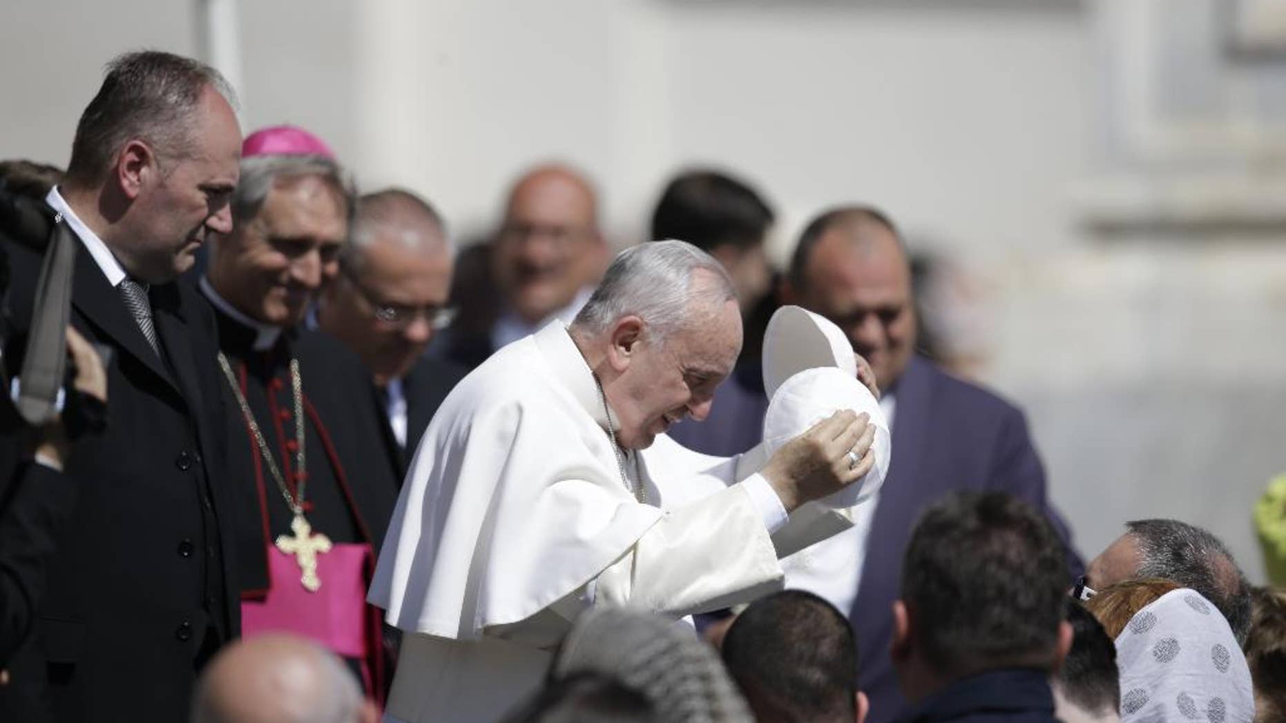 Pope Francis, center, exchanges his skull cap with one donated to him by a pilgrim as he leaves at the end of his weekly general audience, in St. Peter's Square, at the Vatican, Wednesday, April 22, 2015. (AP Photo/Gregorio Borgia)